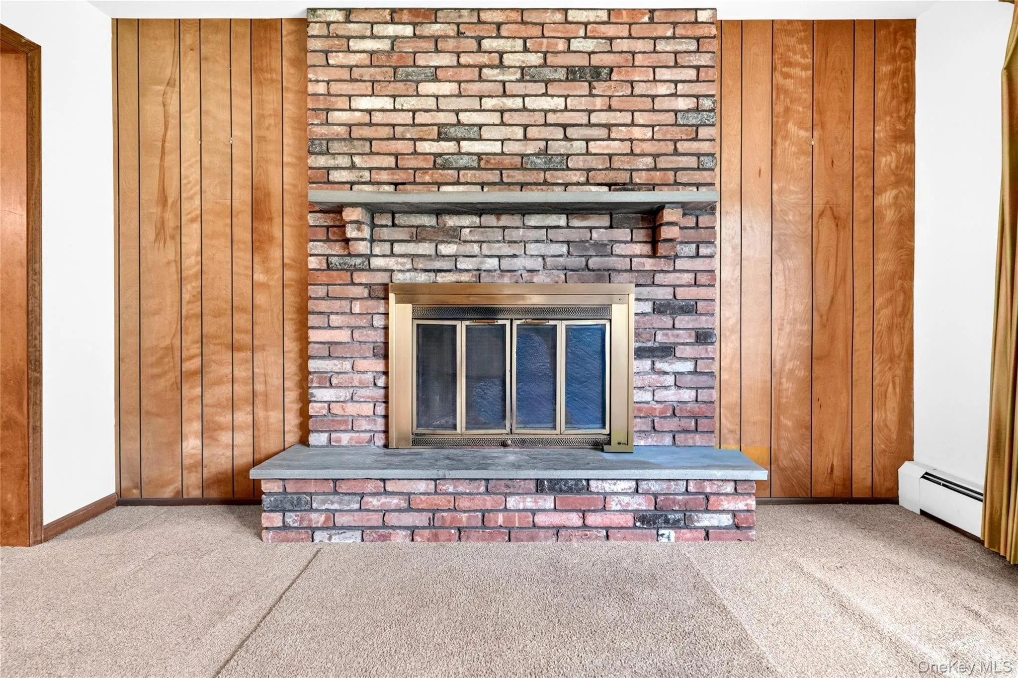 Brick fireplace featuring a metal firebox insert, stone hearth, and mantel Brick fireplace featuring a metal firebox insert, stone hearth, and mantel