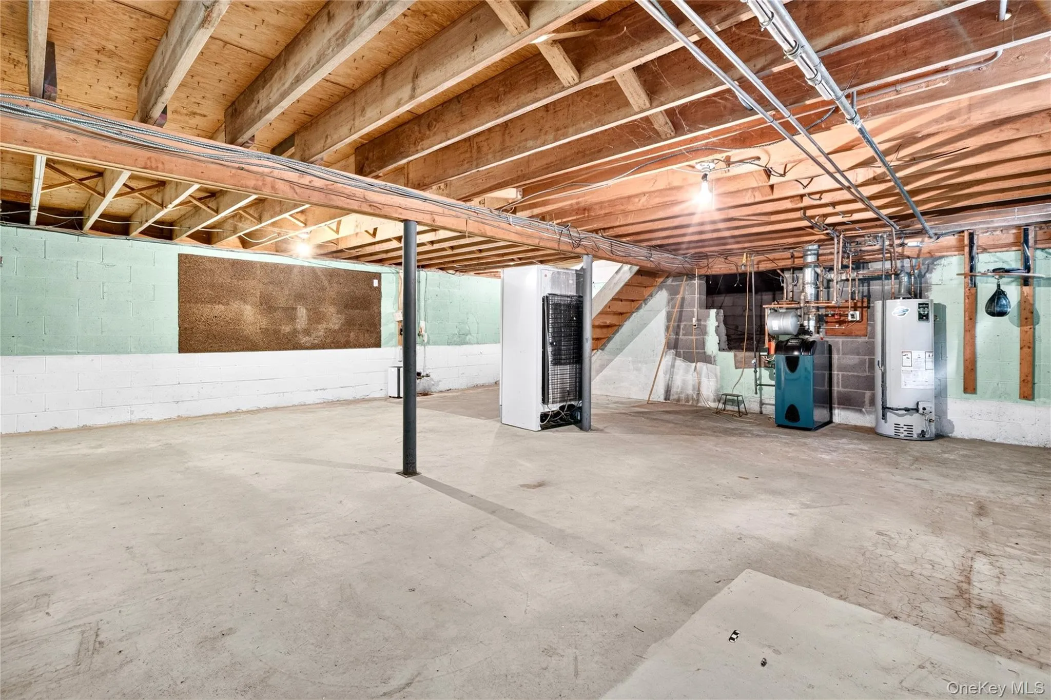 Spacious basement featuring exposed wood ceiling joists, concrete flooring, and painted concrete block walls Spacious basement featuring exposed wood ceiling joists, concrete flooring, and painted concrete block walls