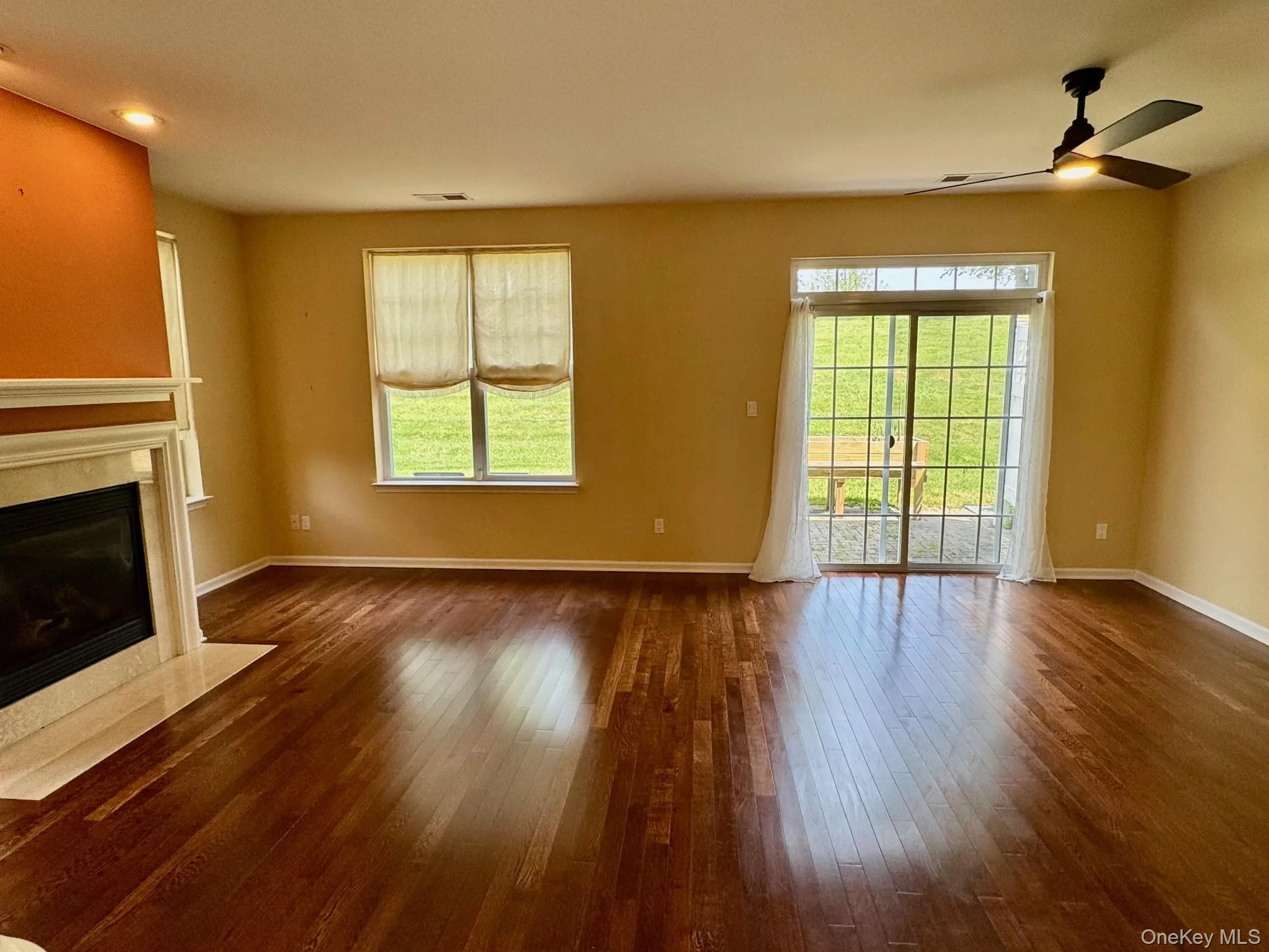 Unfurnished living room with a premium fireplace, dark wood-style flooring, and a ceiling fan Unfurnished living room with a premium fireplace, dark wood-style flooring, and a ceiling fan