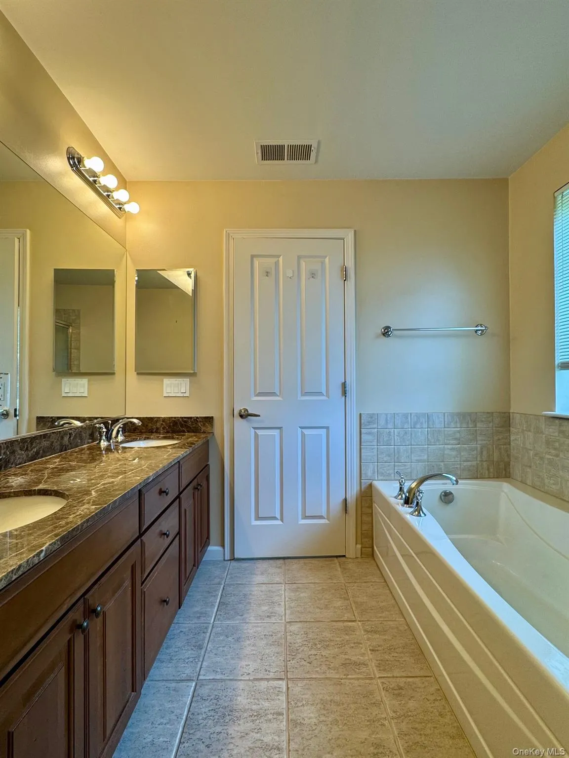 Bathroom with double vanity, a bath, and tile patterned floors Bathroom with double vanity, a bath, and tile patterned floors