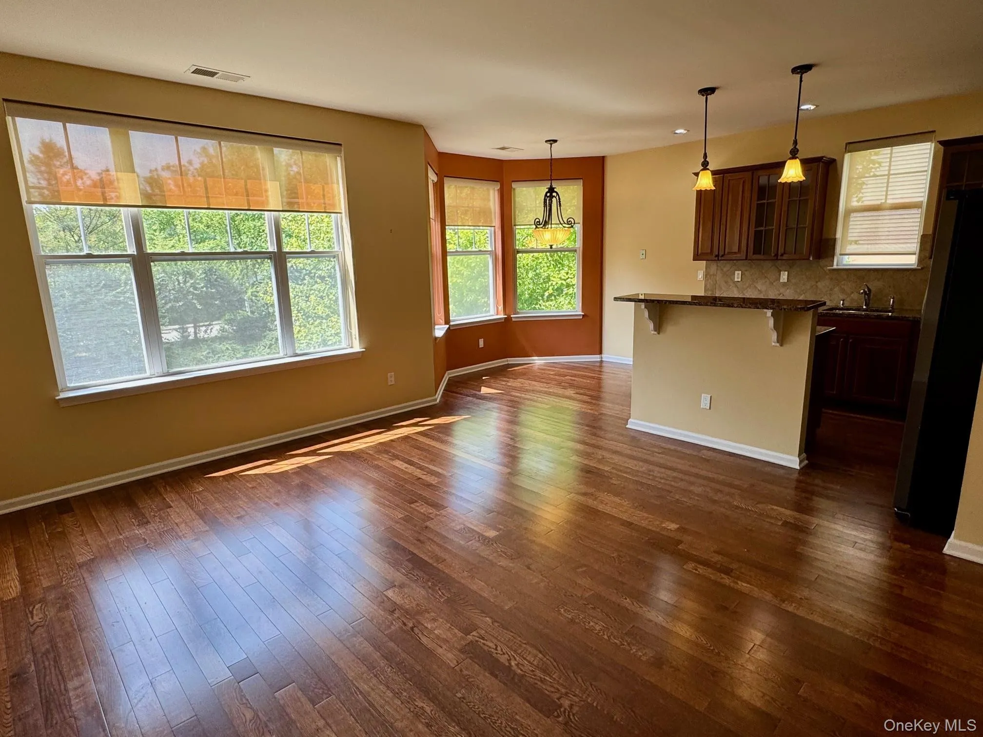 Kitchen featuring a breakfast bar area, freestanding refrigerator, glass insert cabinets, and dark wood finished floors Kitchen featuring a breakfast bar area, freestanding refrigerator, glass insert cabinets, and dark wood finished floors