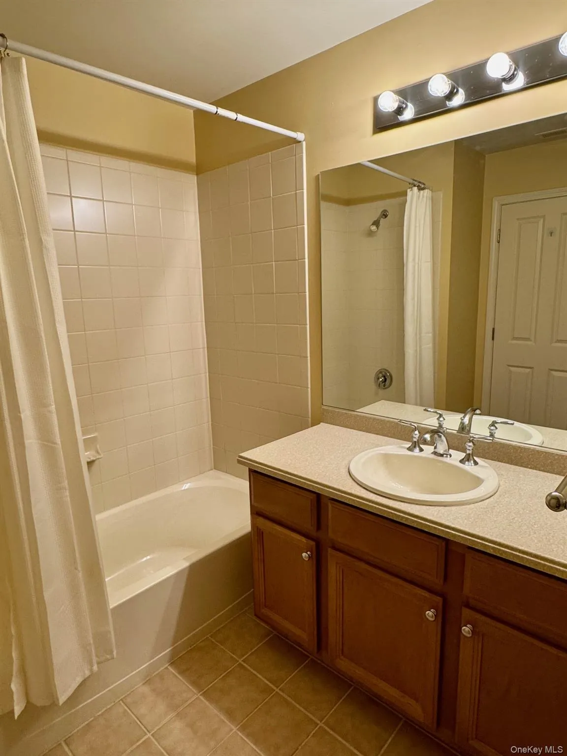 Full bath featuring tile patterned floors, shower / bath combo with shower curtain, and vanity Full bath featuring tile patterned floors, shower / bath combo with shower curtain, and vanity
