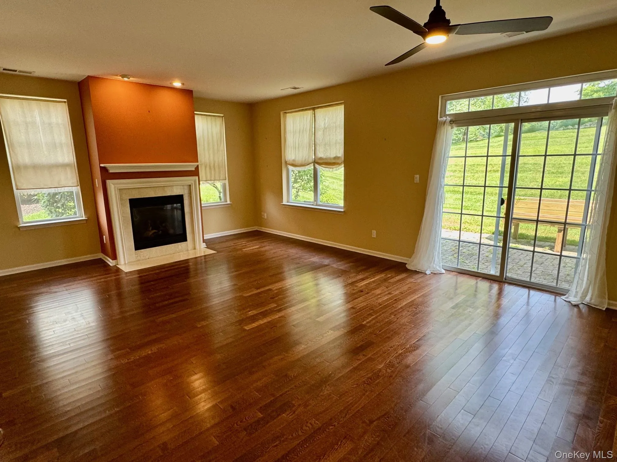 Unfurnished living room featuring a ceiling fan, dark wood finished floors, and a fireplace Unfurnished living room featuring a ceiling fan, dark wood finished floors, and a fireplace