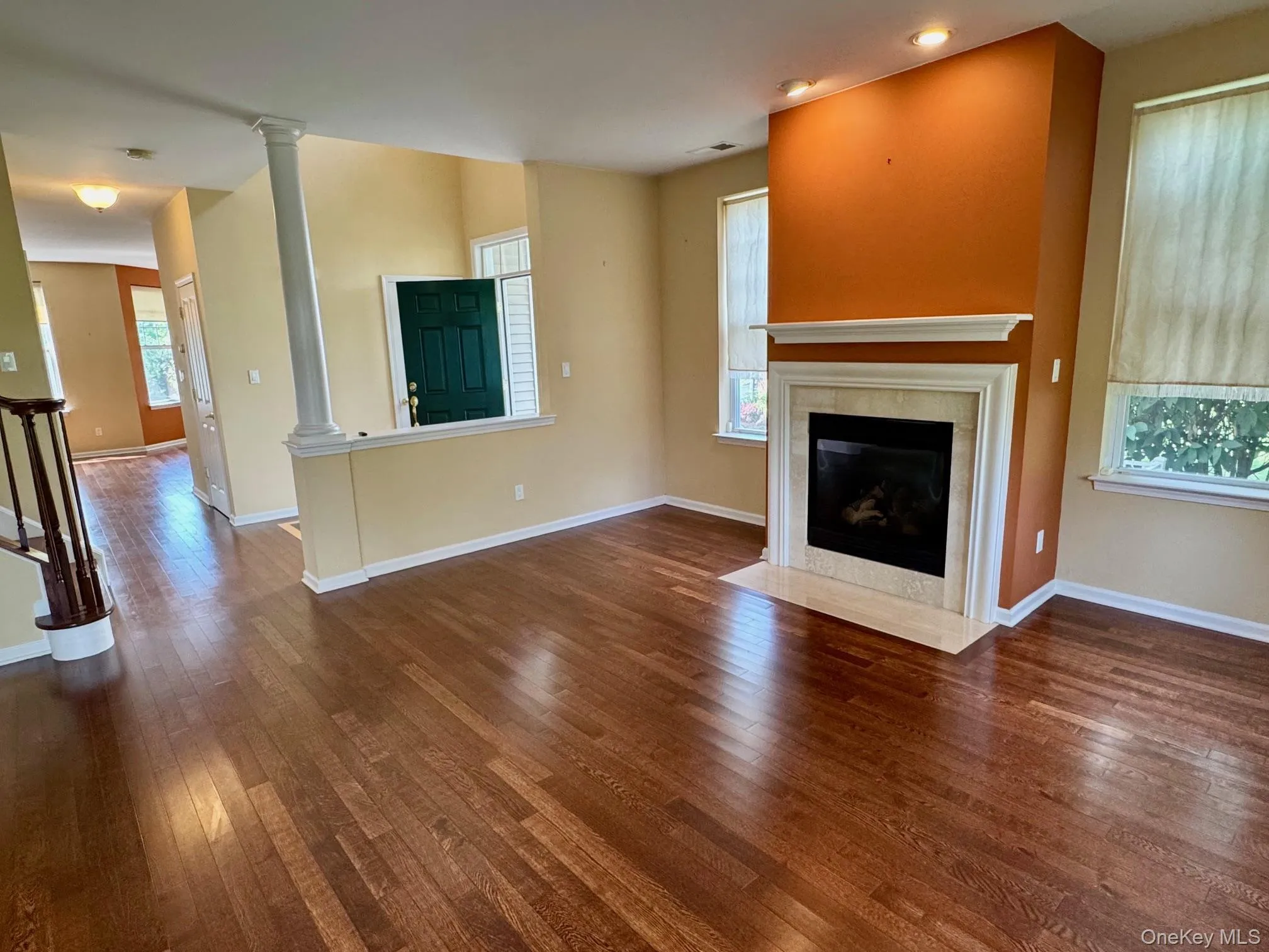 Unfurnished living room featuring wood finished floors, ornate columns, a tile fireplace, and recessed lighting Unfurnished living room featuring wood finished floors, ornate columns, a tile fireplace, and recessed lighting