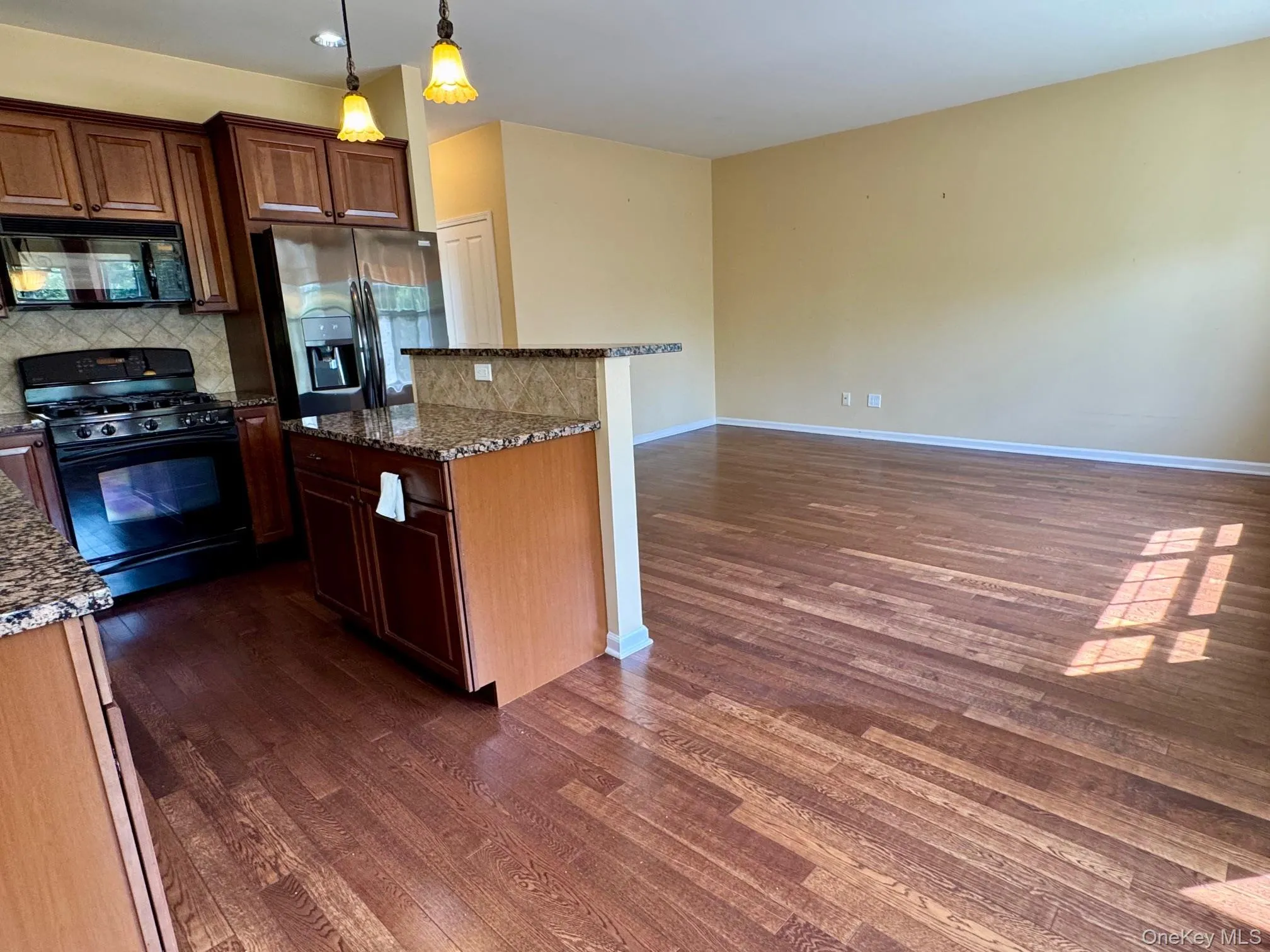 Kitchen featuring black appliances, dark wood-style floors, and tasteful backsplash Kitchen featuring black appliances, dark wood-style floors, and tasteful backsplash