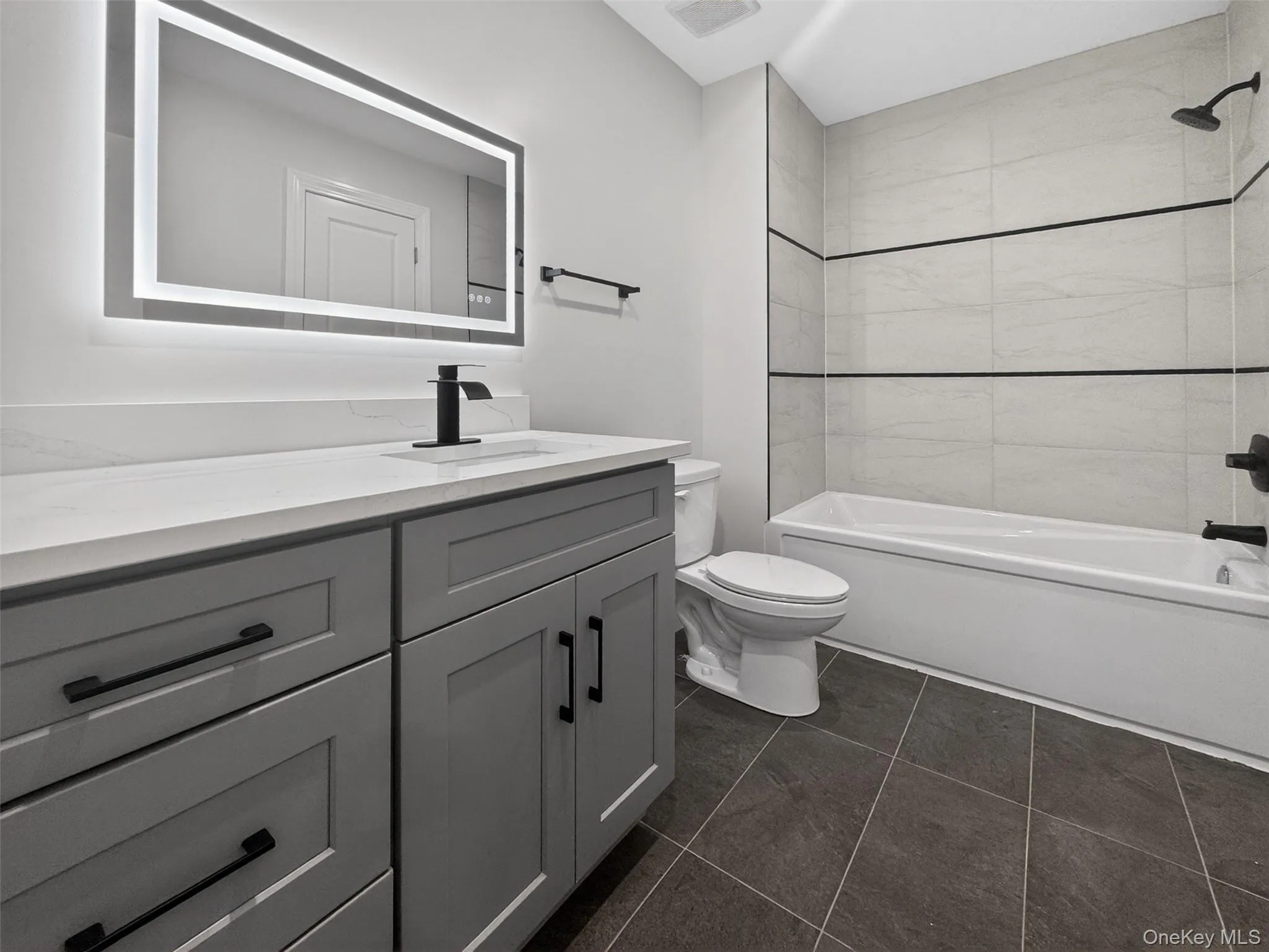 Modern bathroom featuring a single vanity with a light gray cabinet, quartz countertop, and matte black fixtures Modern bathroom featuring a single vanity with a light gray cabinet, quartz countertop, and matte black fixtures
