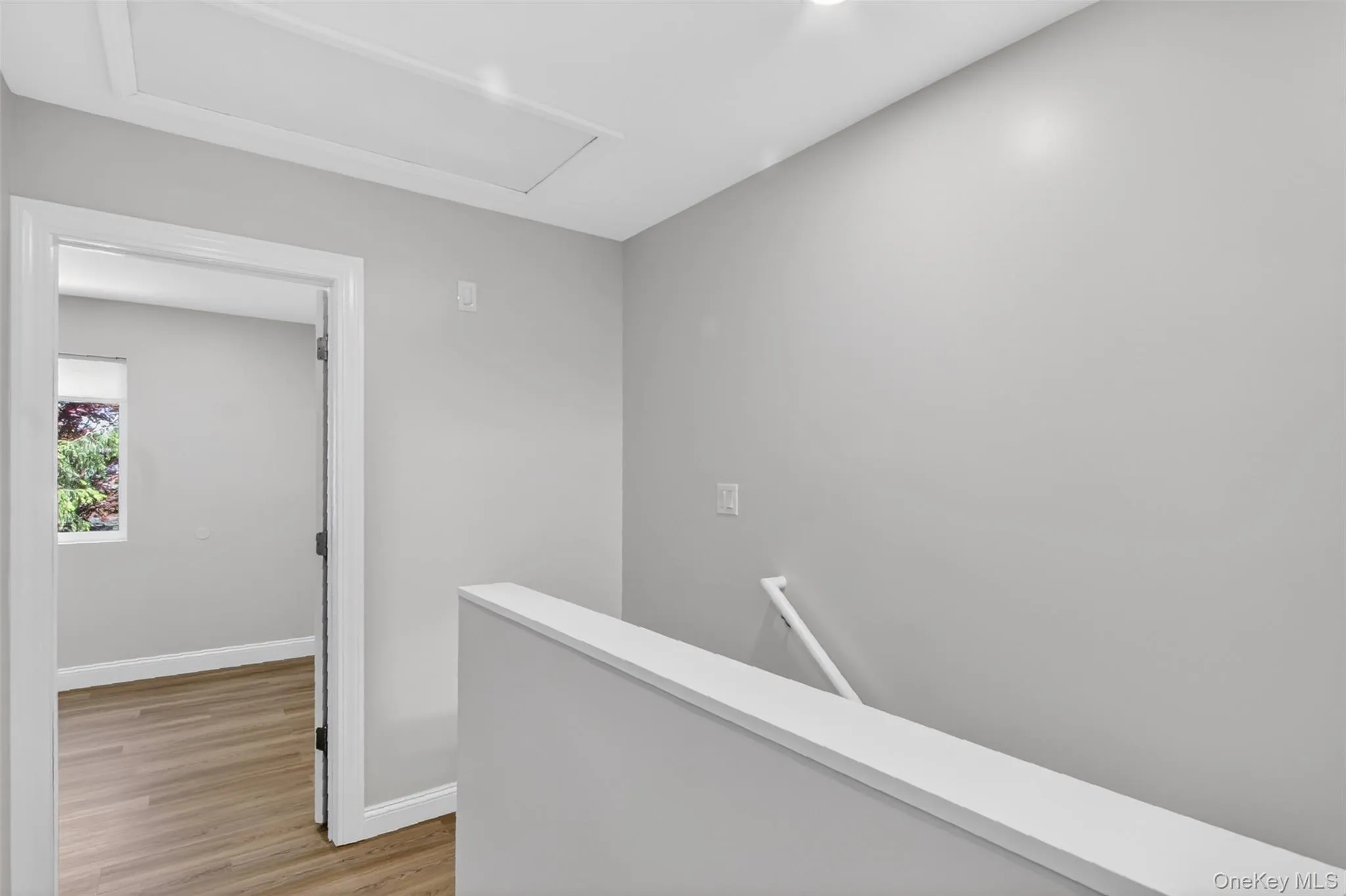 Interior hallway with light gray walls, white trim, recessed lighting, and an access panel in the ceiling Interior hallway with light gray walls, white trim, recessed lighting, and an access panel in the ceiling