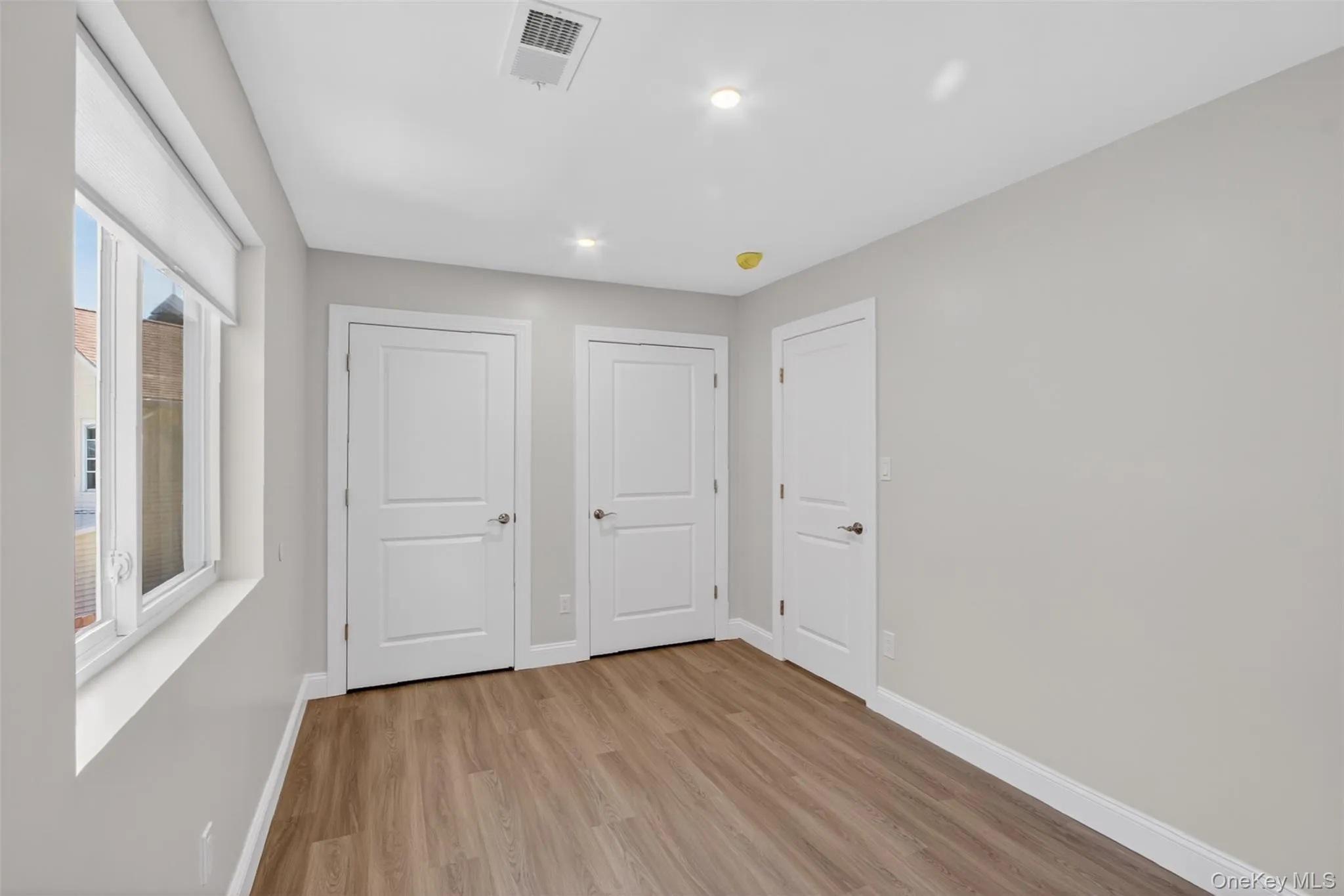 Interior room featuring light wood-finish flooring, light gray painted walls, and white trim Interior room featuring light wood-finish flooring, light gray painted walls, and white trim