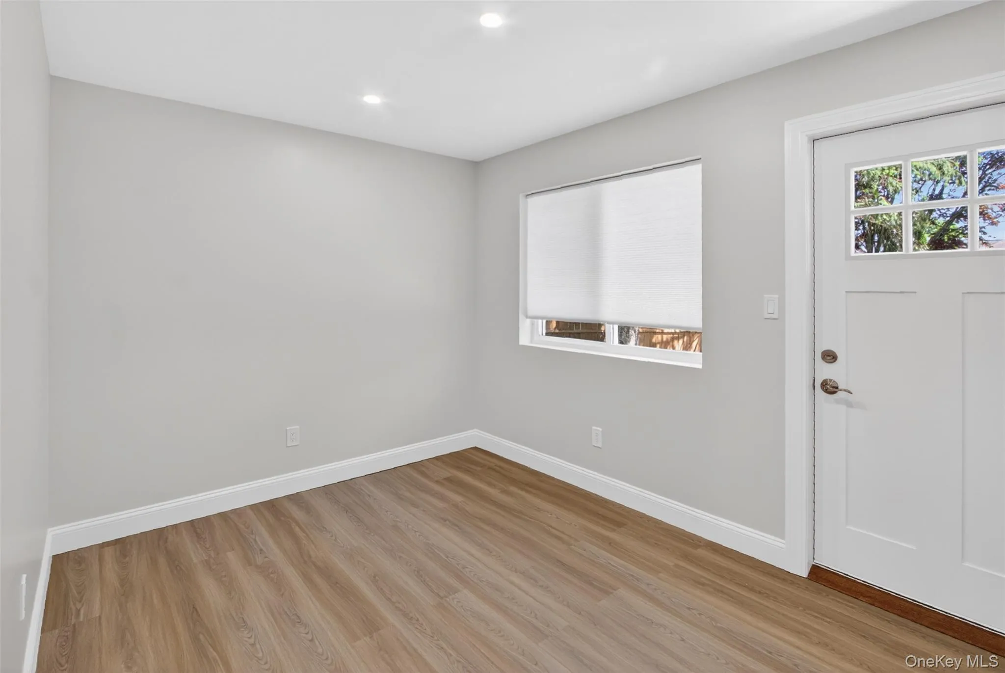 Bright interior space featuring light grey walls, wood-finish flooring, and recessed ceiling lighting Bright interior space featuring light grey walls, wood-finish flooring, and recessed ceiling lighting