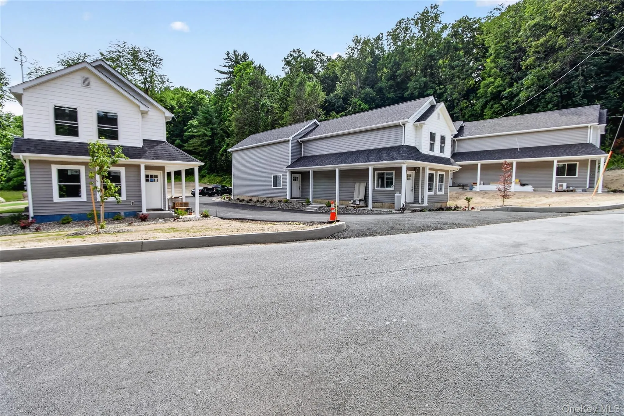 New construction residential buildings featuring light gray siding, white trim, and covered front porches New construction residential buildings featuring light gray siding, white trim, and covered front porches