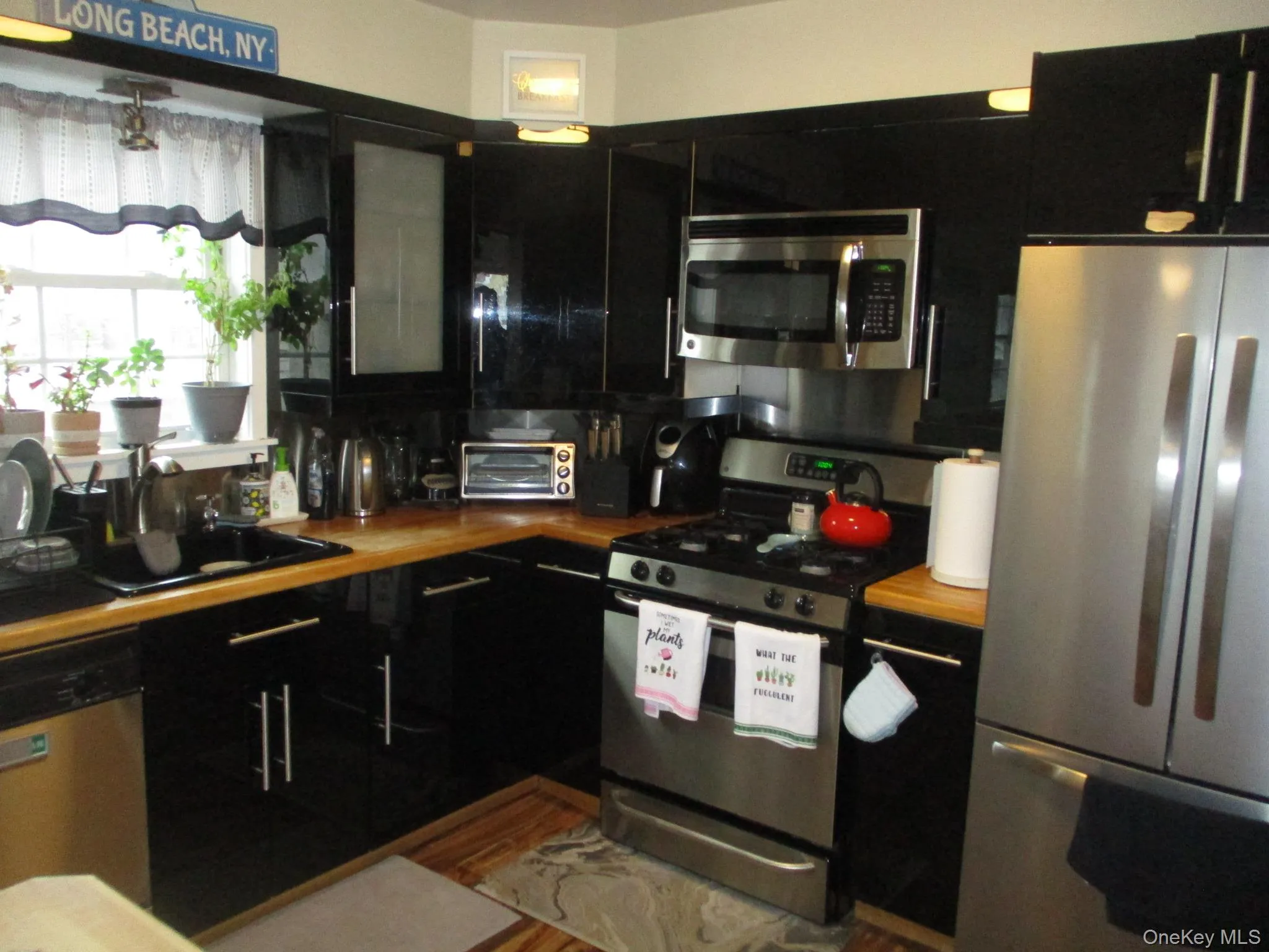Kitchen featuring a sink, dark cabinetry, wood counters, stainless steel appliances, and a toaster Kitchen featuring a sink, dark cabinetry, wood counters, stainless steel appliances, and a toaster