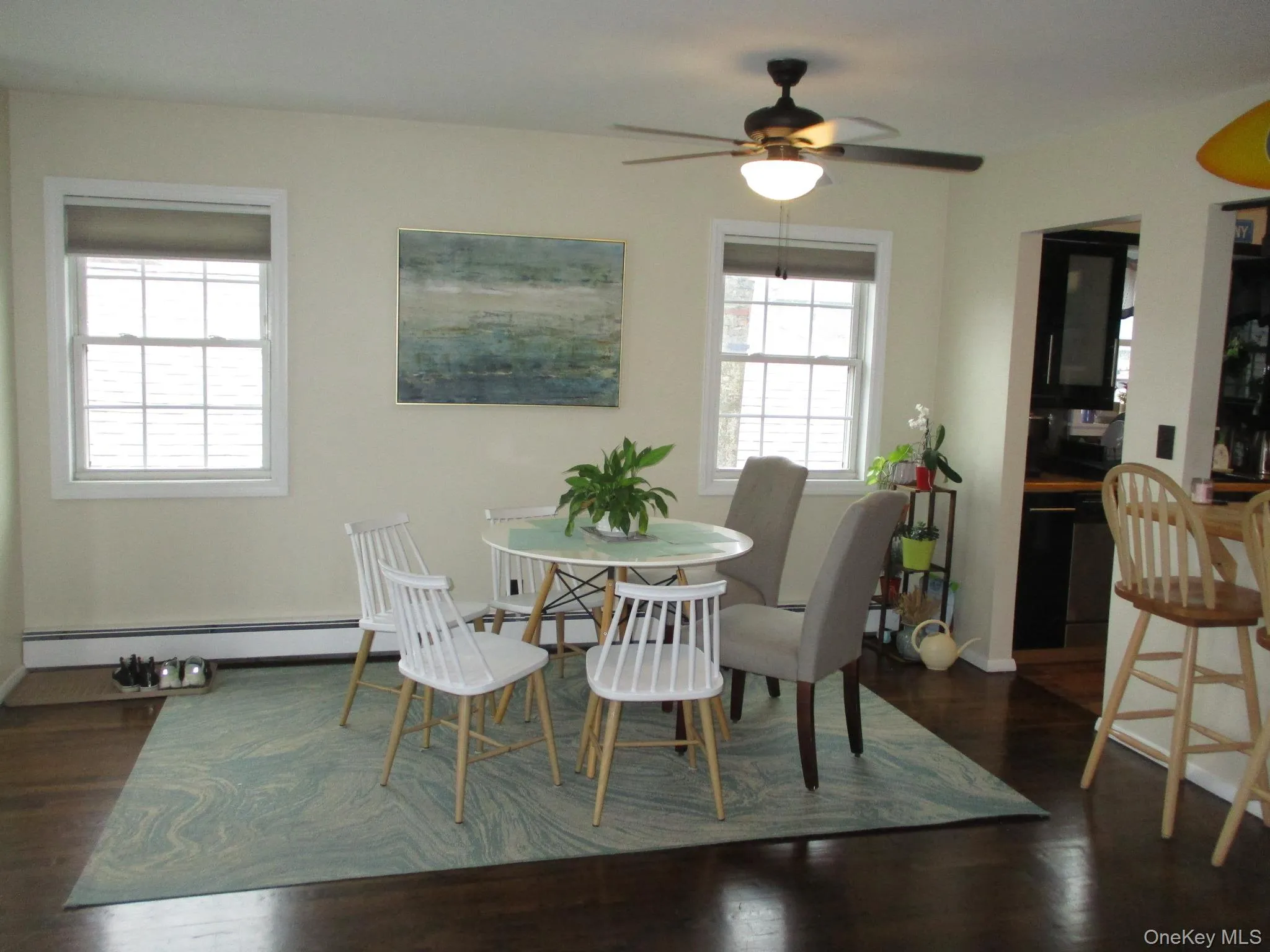 Dining space with a baseboard radiator, a ceiling fan, and dark wood-style floors Dining space with a baseboard radiator, a ceiling fan, and dark wood-style floors