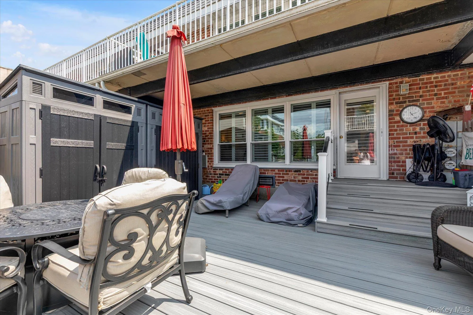 Spacious outdoor deck featuring gray composite decking and a brick exterior Spacious outdoor deck featuring gray composite decking and a brick exterior