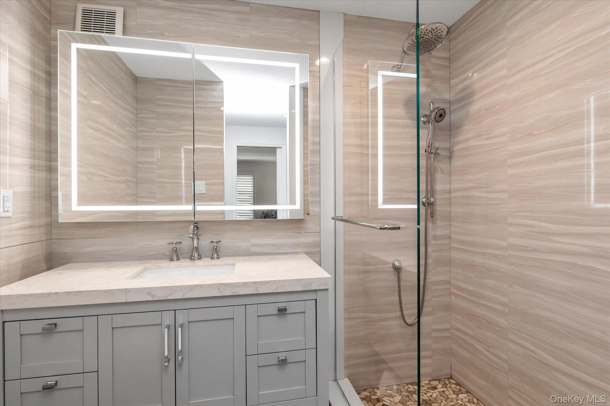 Primary Ensuite bathroom featuring a glass-enclosed shower with pebble flooring and a rainfall showerhead Primary Ensuite bathroom featuring a glass-enclosed shower with pebble flooring and a rainfall showerhead