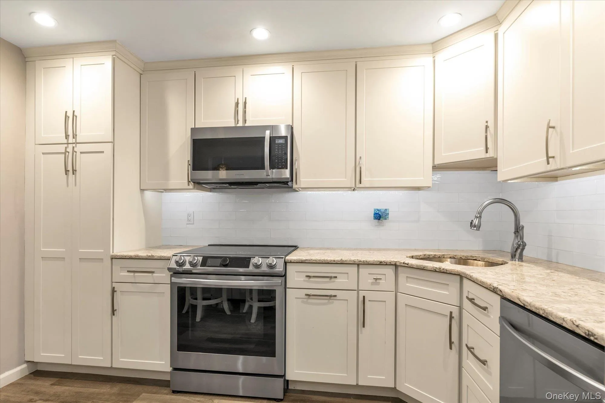 Kitchen featuring neutral cabinetry, stainless steel appliances, speckled stone countertops, a white subway tile backsplash, and recessed lighting Kitchen featuring neutral cabinetry, stainless steel appliances, speckled stone countertops, a white subway tile backsplash, and recessed lighting