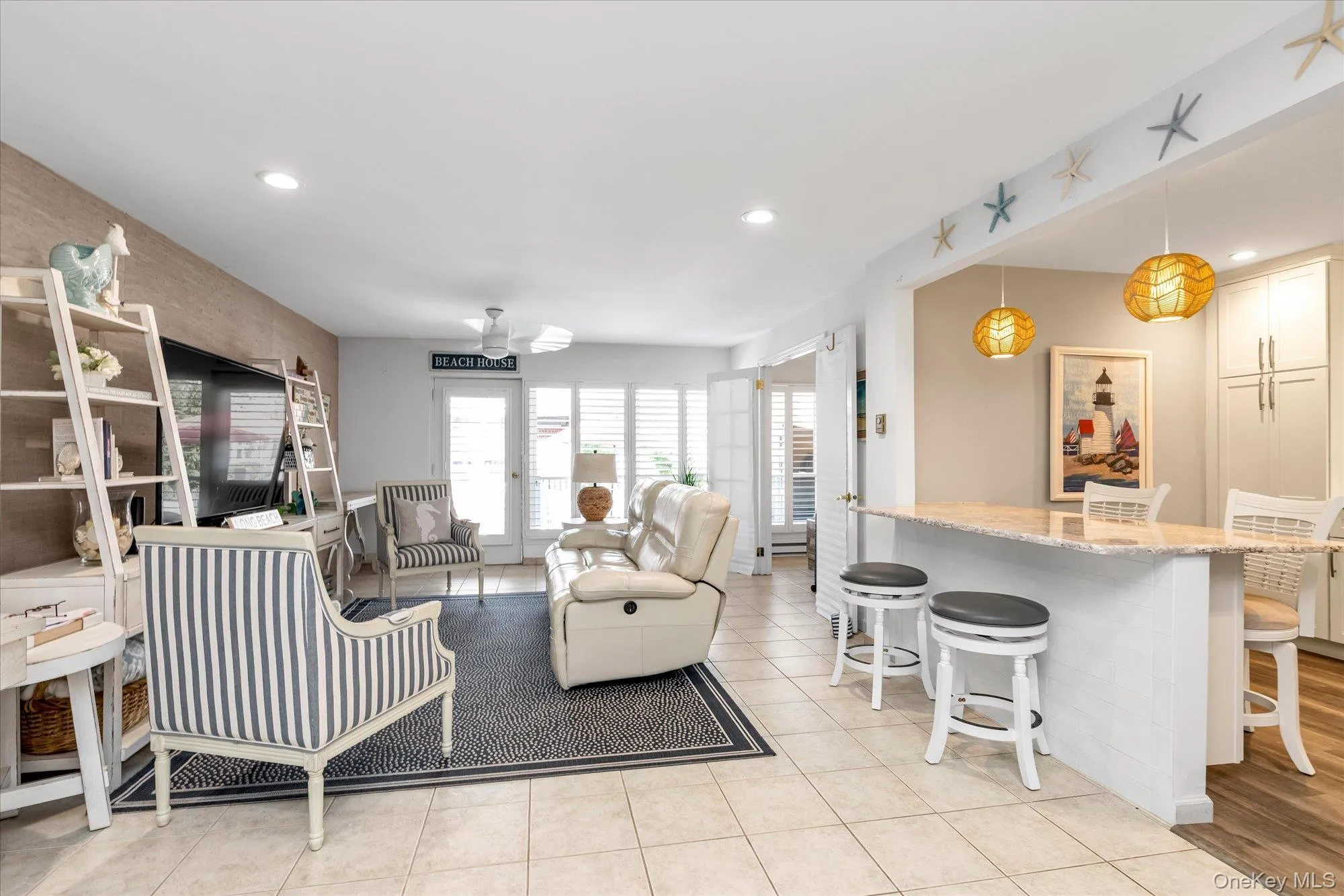 Open-concept living area featuring neutral tile flooring, a breakfast bar with a granite countertop, recessed lighting, and a ceiling fan Open-concept living area featuring neutral tile flooring, a breakfast bar with a granite countertop, recessed lighting, and a ceiling fan