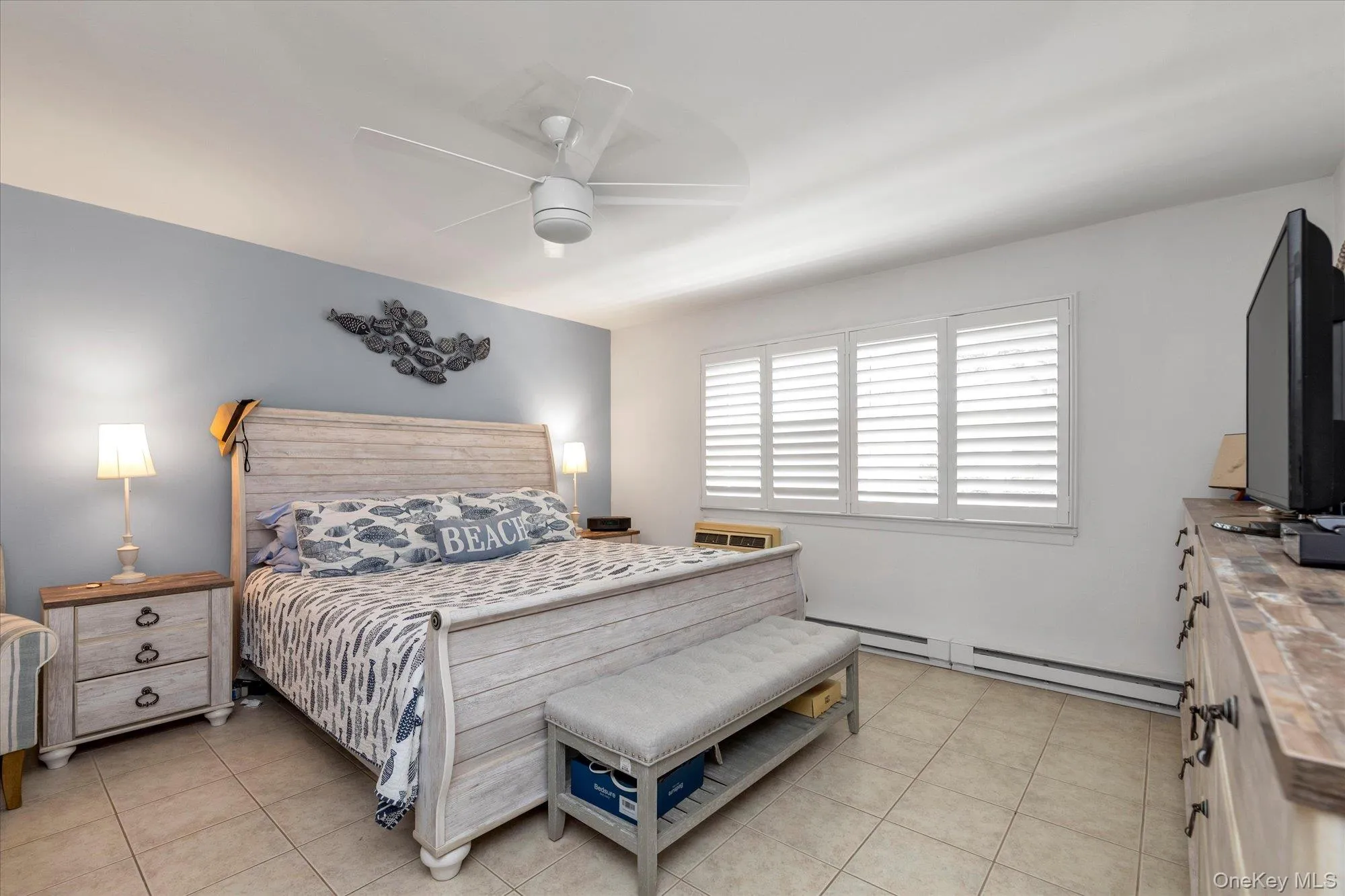 Featuring a ceiling fan, wall-mounted artwork, window with louvered shutters, and tile flooring Featuring a ceiling fan, wall-mounted artwork, window with louvered shutters, and tile flooring