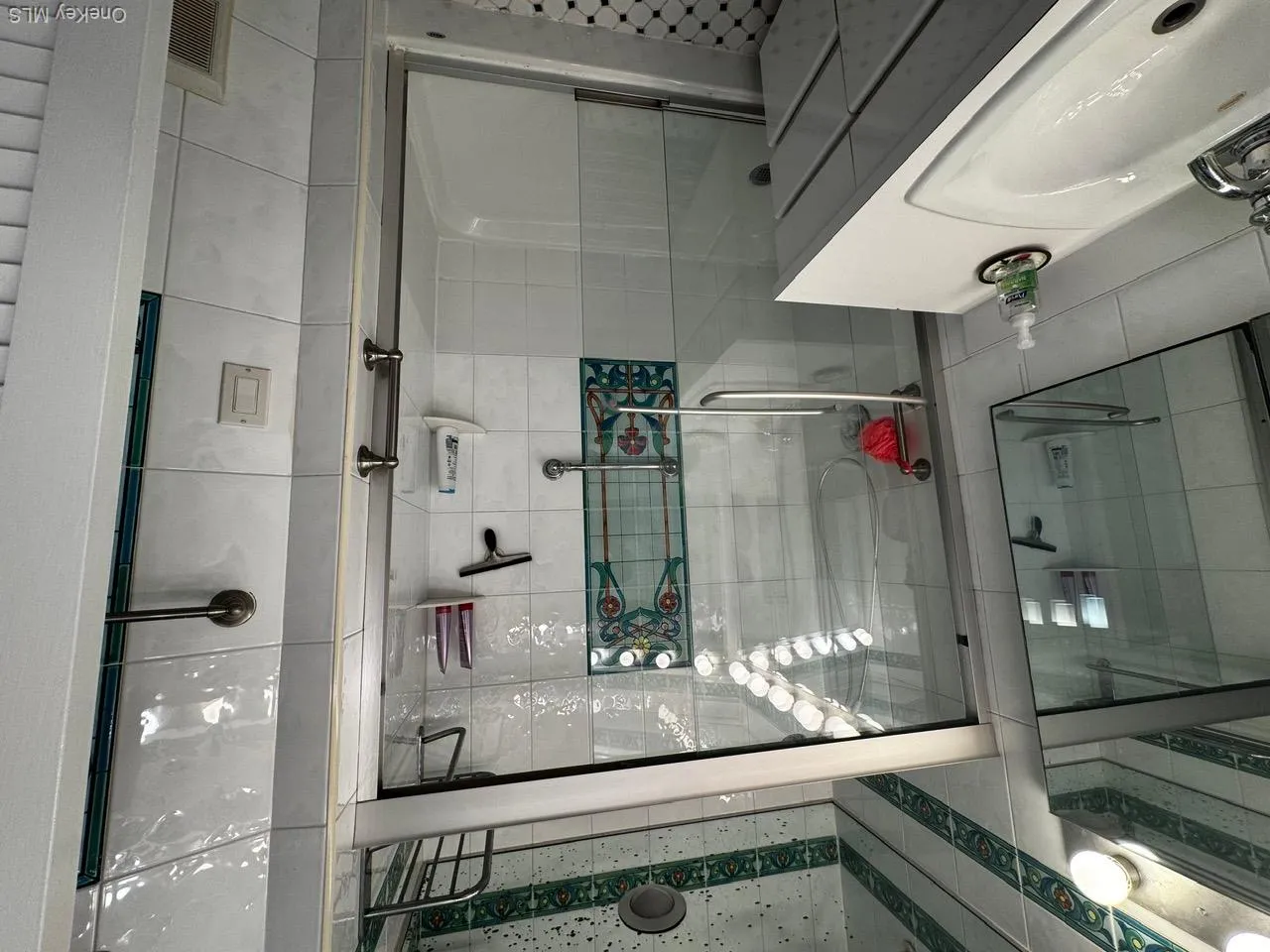 Bathroom featuring a stall shower, vanity, and tile walls Bathroom featuring a stall shower, vanity, and tile walls