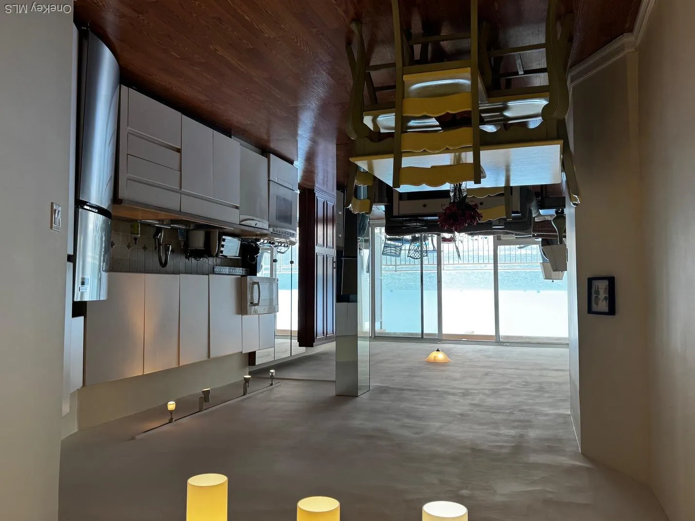 Kitchen featuring dark wood-style flooring, fridge, dark countertops, dishwashing machine, and white cabinetry Kitchen featuring dark wood-style flooring, fridge, dark countertops, dishwashing machine, and white cabinetry