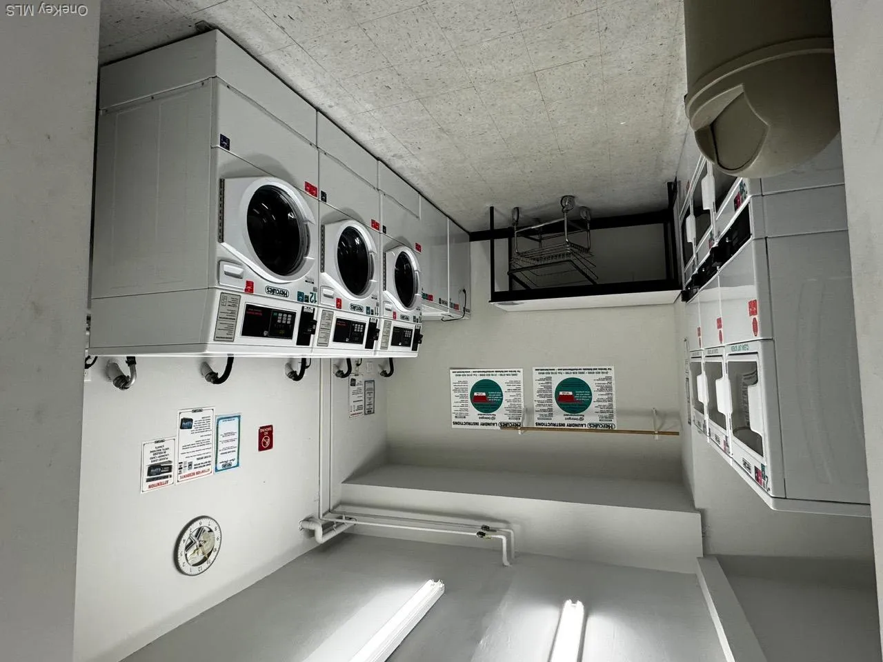 Community laundry room with stacked washer and clothes dryer, light flooring, and washer and clothes dryer Community laundry room with stacked washer and clothes dryer, light flooring, and washer and clothes dryer