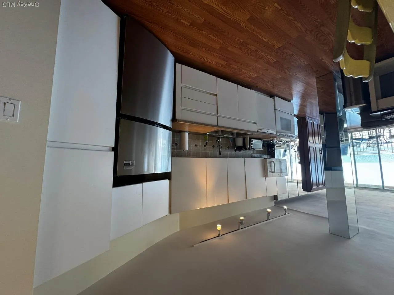 Kitchen featuring dark wood-type flooring, refrigerator, decorative backsplash, white cabinets, and dishwasher Kitchen featuring dark wood-type flooring, refrigerator, decorative backsplash, white cabinets, and dishwasher