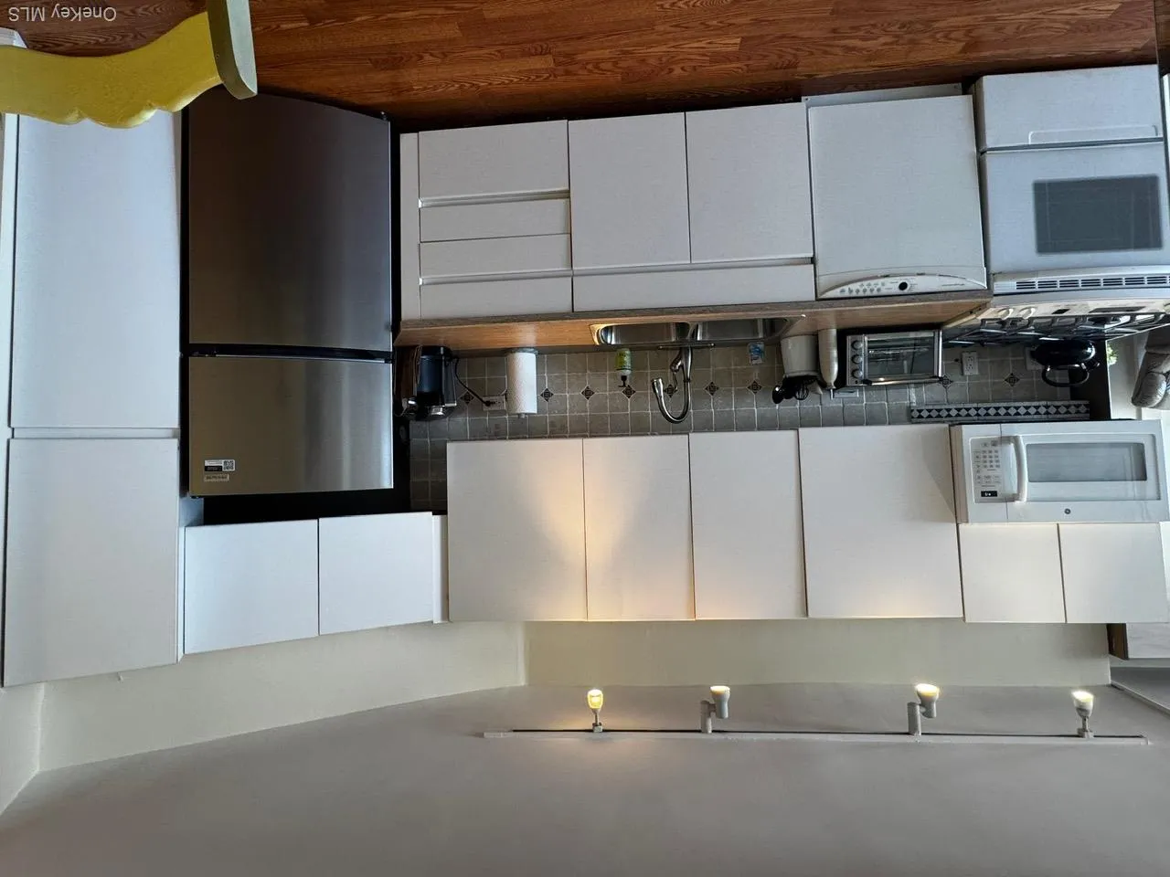 Kitchen with fridge, decorative backsplash, stove, dark wood-style floors, and dishwashing machine Kitchen with fridge, decorative backsplash, stove, dark wood-style floors, and dishwashing machine