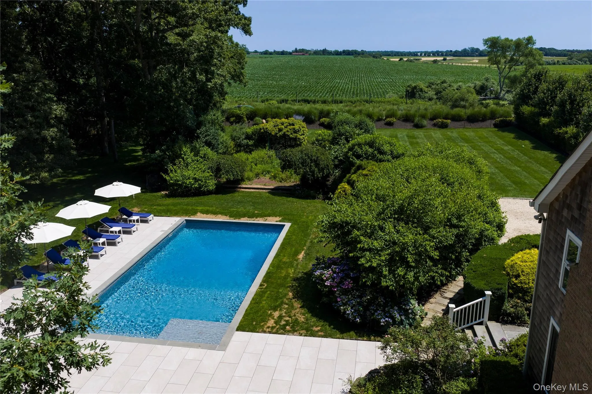 Rectangular swimming pool with a stone paver surround, farm field views Rectangular swimming pool with a stone paver surround, farm field views