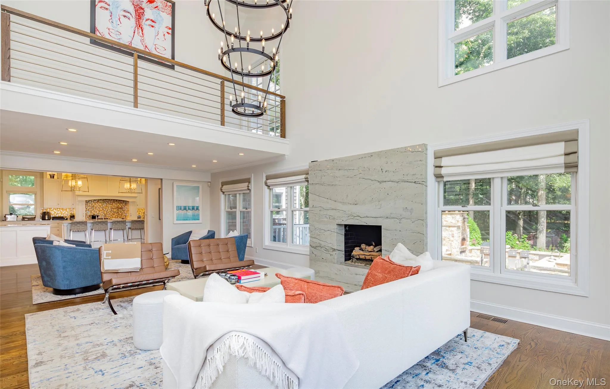 Two-story living area featuring a stone fireplace with a raised hearth, high ceilings, and wood-finish flooring Two-story living area featuring a stone fireplace with a raised hearth, high ceilings, and wood-finish flooring