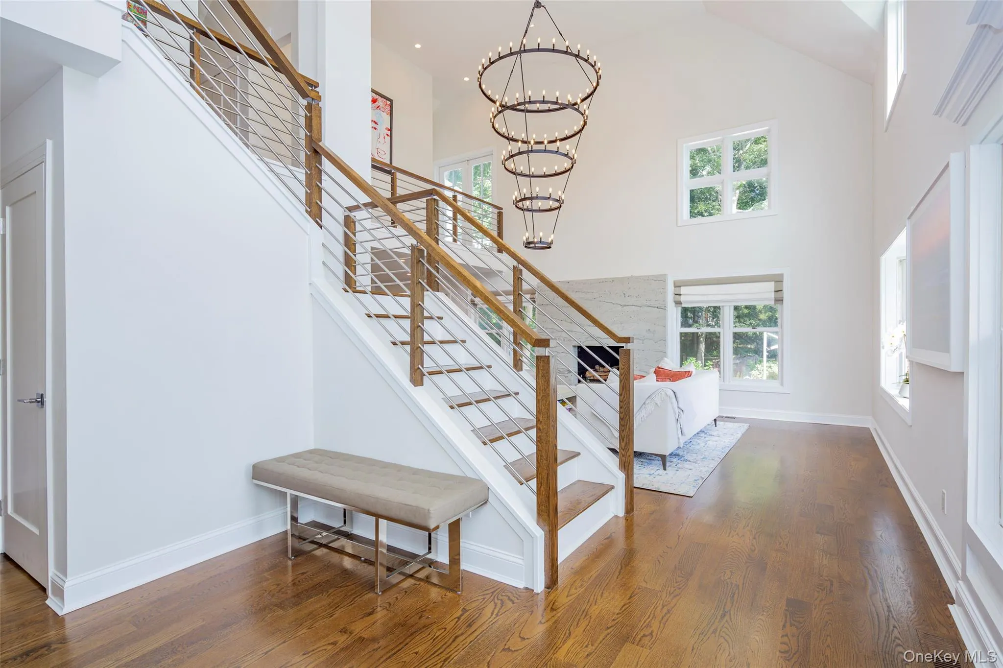 Open-concept entry foyer featuring a grand staircase with wood railings and cable balusters Open-concept entry foyer featuring a grand staircase with wood railings and cable balusters