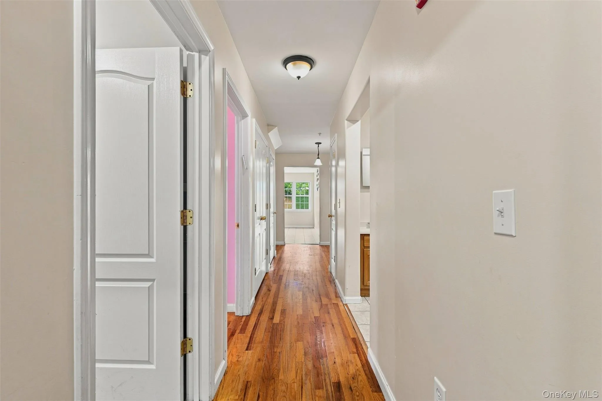 Hallway featuring wood-finish flooring extending into the background Hallway featuring wood-finish flooring extending into the background