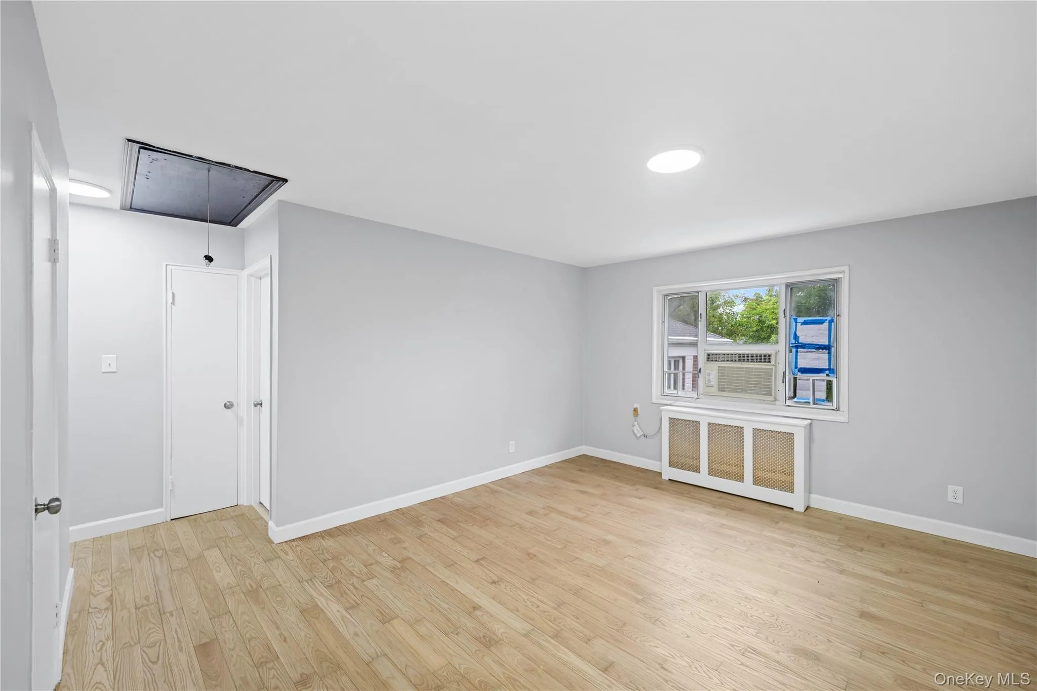Spacious room featuring light wood-finish flooring, light gray wall paint, and white trim Spacious room featuring light wood-finish flooring, light gray wall paint, and white trim