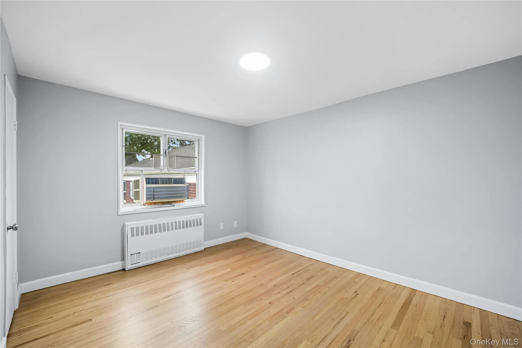 Room with light gray walls and wood-finish flooring Room with light gray walls and wood-finish flooring