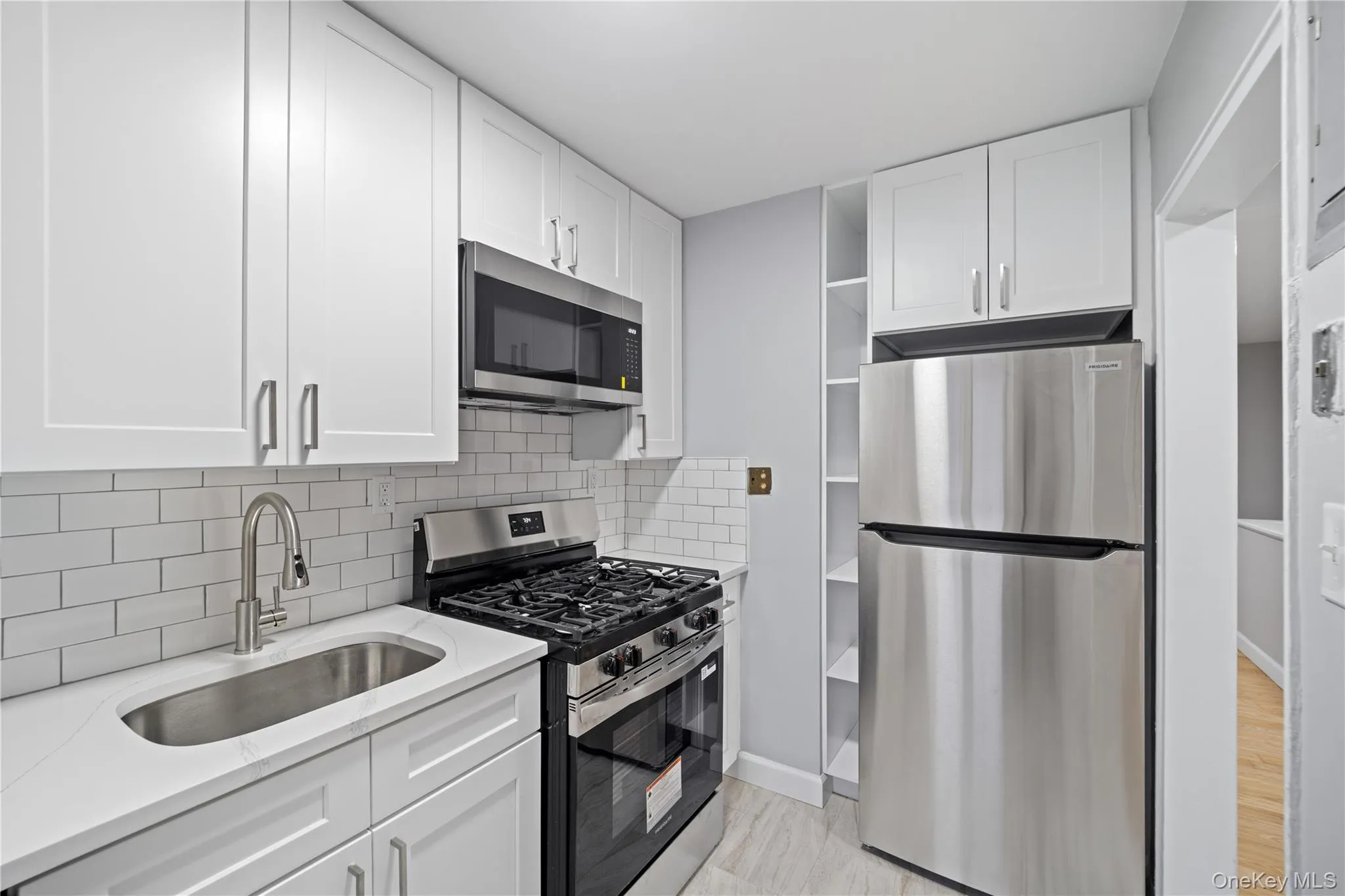 Kitchen featuring white shaker-style cabinetry, subway tile backsplash, stainless steel appliances, a gas range, and a single basin undermount sink Kitchen featuring white shaker-style cabinetry, subway tile backsplash, stainless steel appliances, a gas range, and a single basin undermount sink