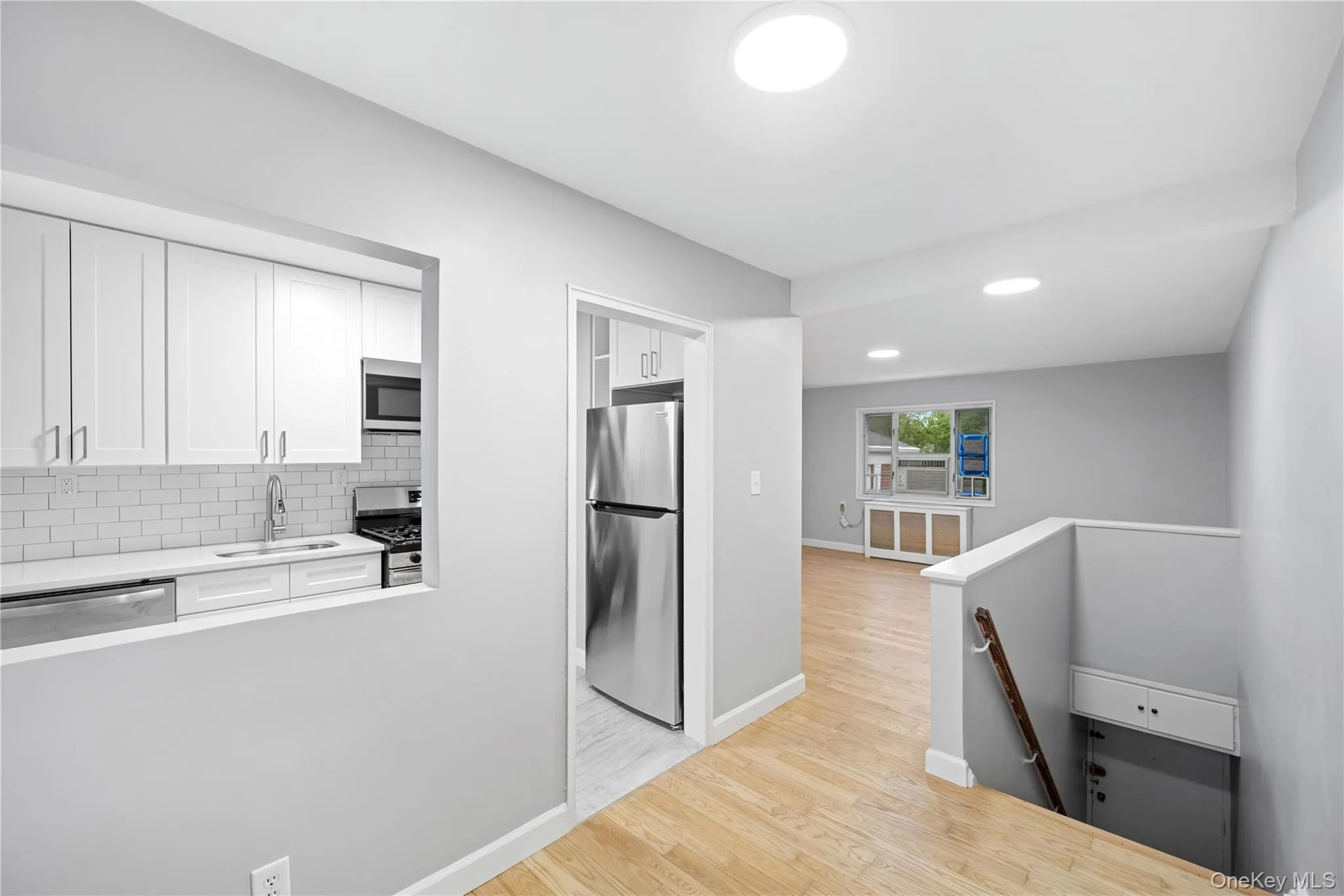 Open-concept kitchen featuring white shaker cabinetry, subway tile backsplash, and stainless steel appliances Open-concept kitchen featuring white shaker cabinetry, subway tile backsplash, and stainless steel appliances