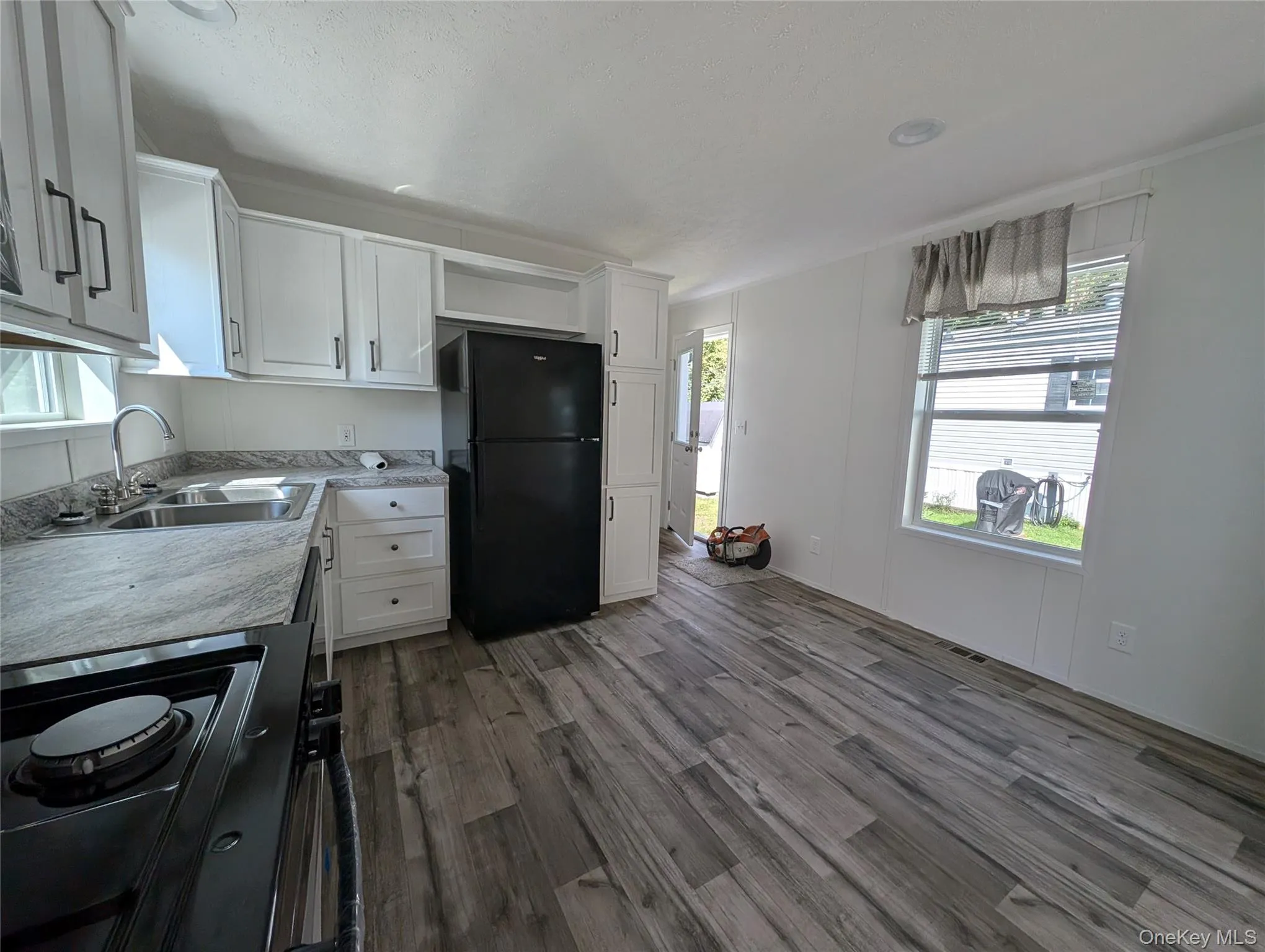 Kitchen with white cabinetry, a sink, black appliances, and dark wood-type flooring Kitchen with white cabinetry, a sink, black appliances, and dark wood-type flooring