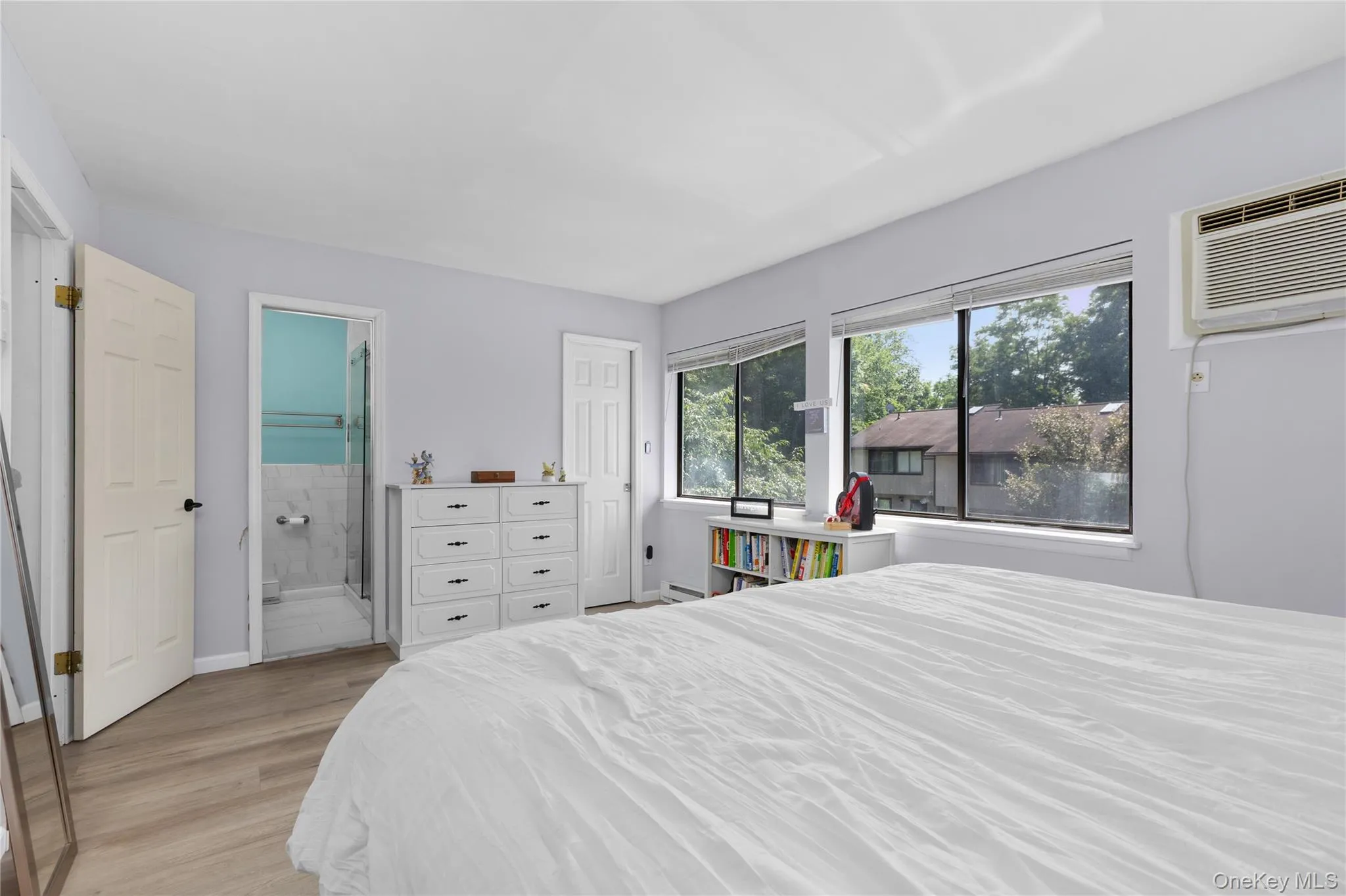 Primary bedroom featuring vinyl flooring accommodates a king or queen size bed set with view of primary bathroom and walk in closet Primary bedroom featuring vinyl flooring accommodates a king or queen size bed set with view of primary bathroom and walk in closet