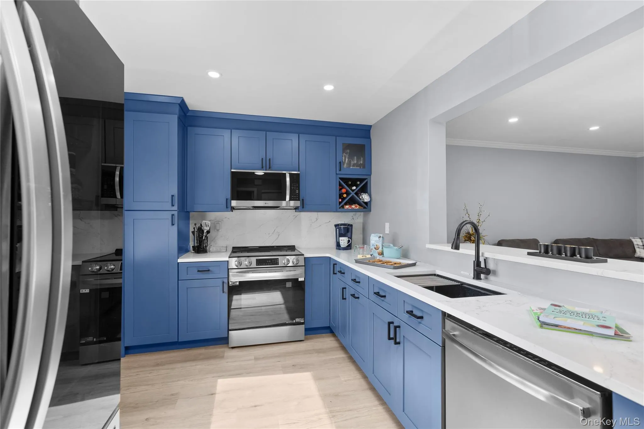 Contemporary kitchen featuring breakfast nook, bright blue cabinetry, light vinyl flooring, recessed lighting, and stainless steel appliances Contemporary kitchen featuring breakfast nook, bright blue cabinetry, light vinyl flooring, recessed lighting, and stainless steel appliances