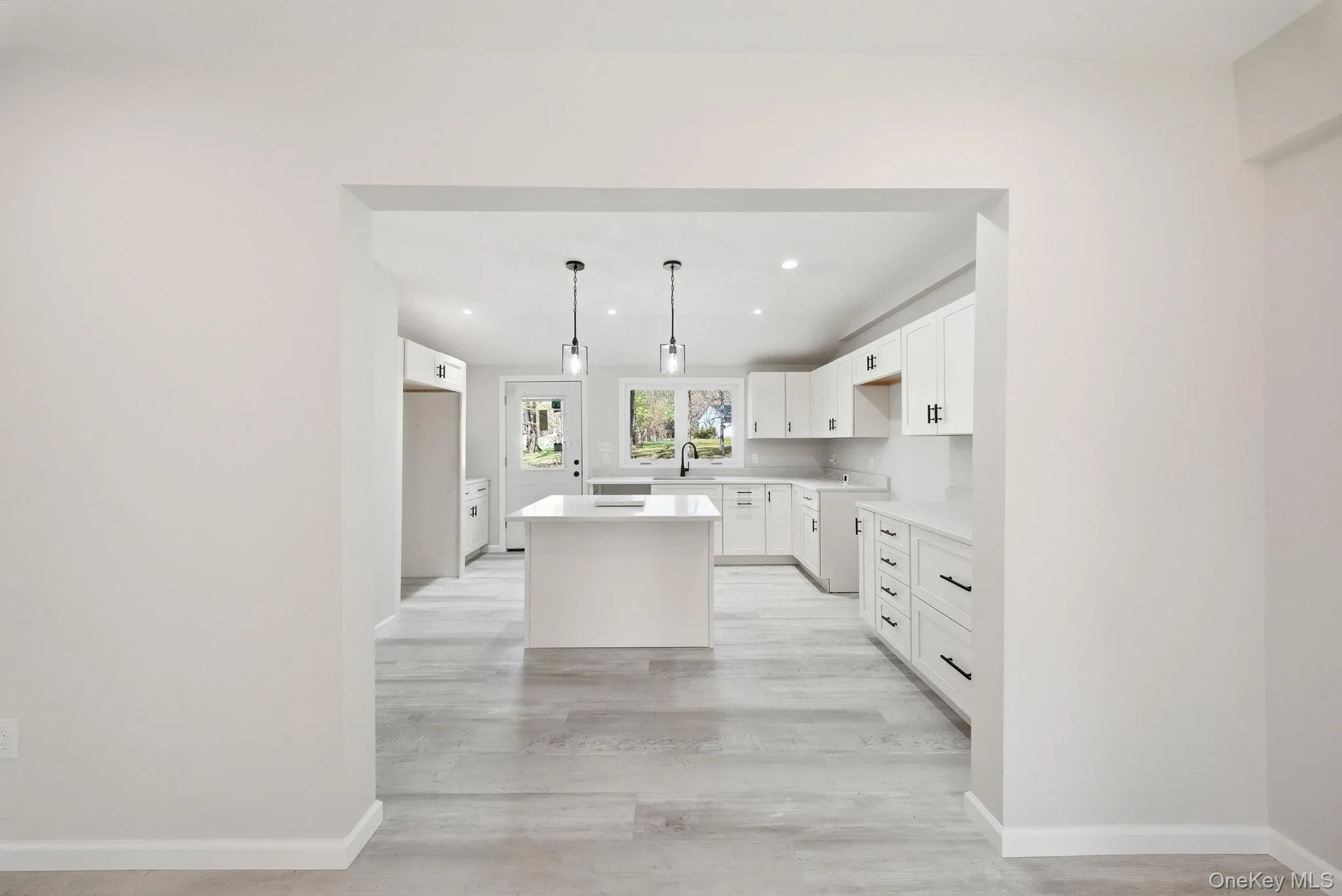Bright kitchen featuring white cabinetry, a central island, recessed lighting, pendant light fixtures. Bright kitchen featuring white cabinetry, a central island, recessed lighting, pendant light fixtures.
