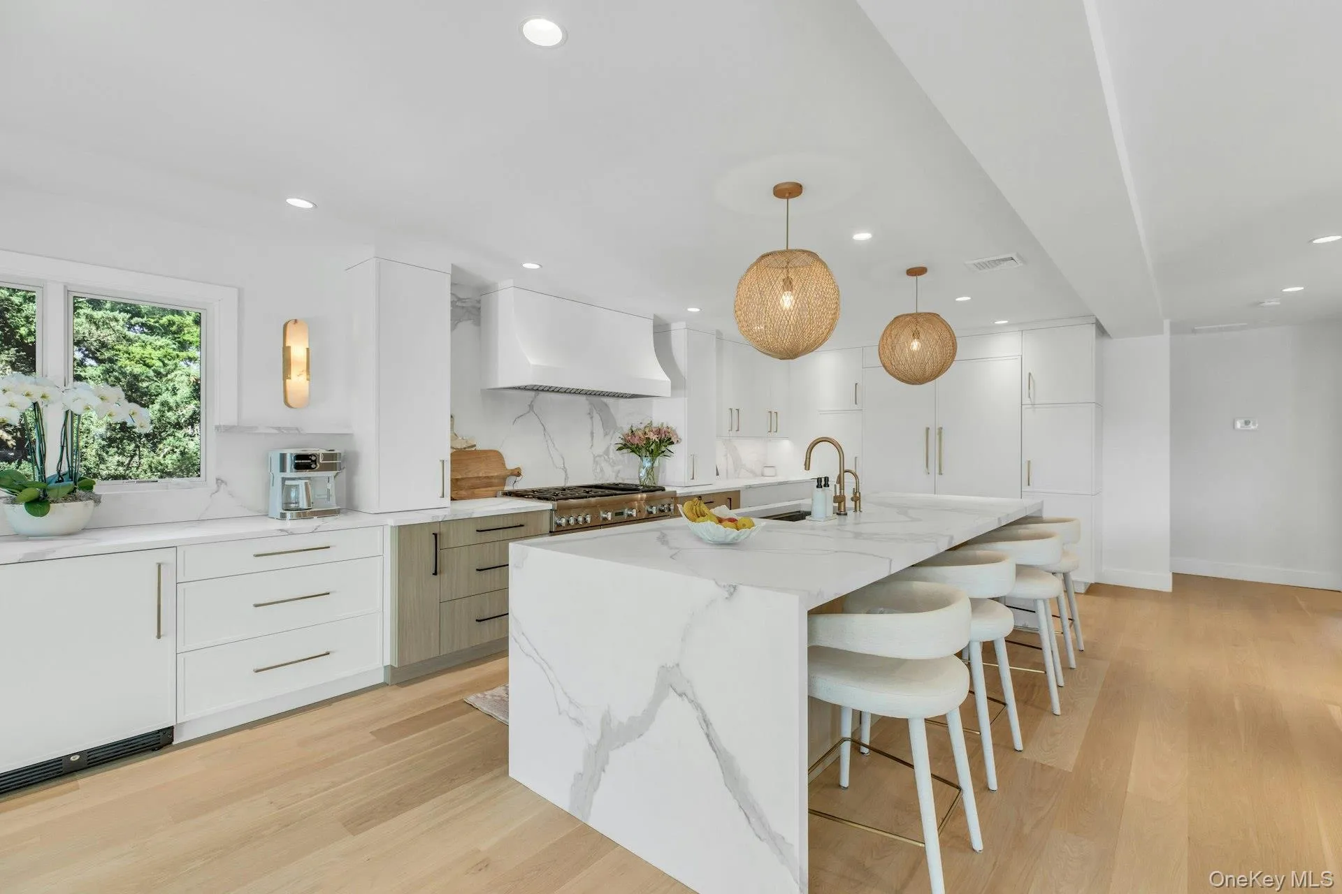 Gourmet kitchen featuring a waterfall island with integrated seating, professional-grade range, full-height cabinetry, wood-finish flooring, and recessed lighting Gourmet kitchen featuring a waterfall island with integrated seating, professional-grade range, full-height cabinetry, wood-finish flooring, and recessed lighting
