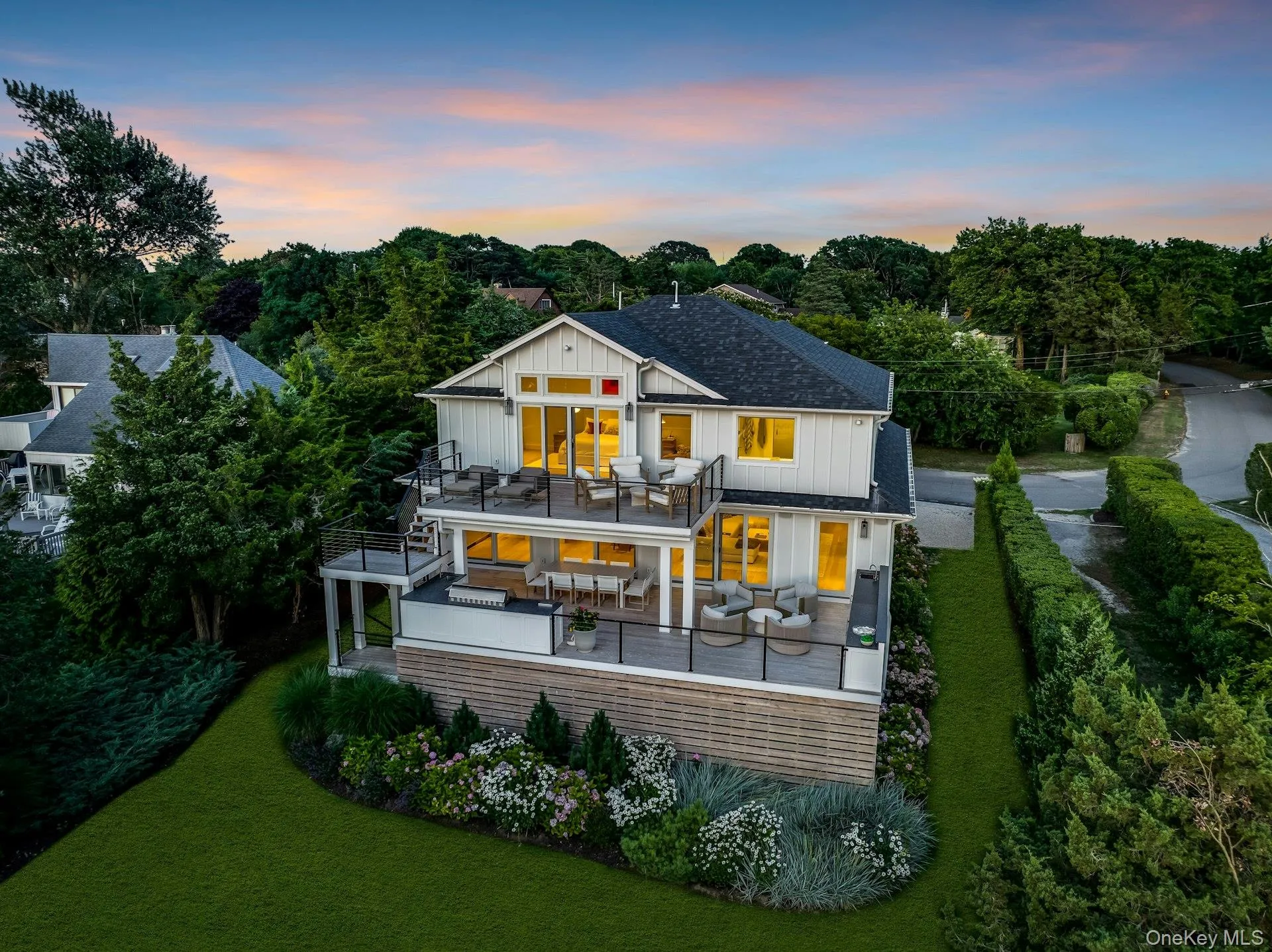 Modern multilevel residence with multiple outdoor decks, a manicured lawn, and mature landscaping Modern multilevel residence with multiple outdoor decks, a manicured lawn, and mature landscaping