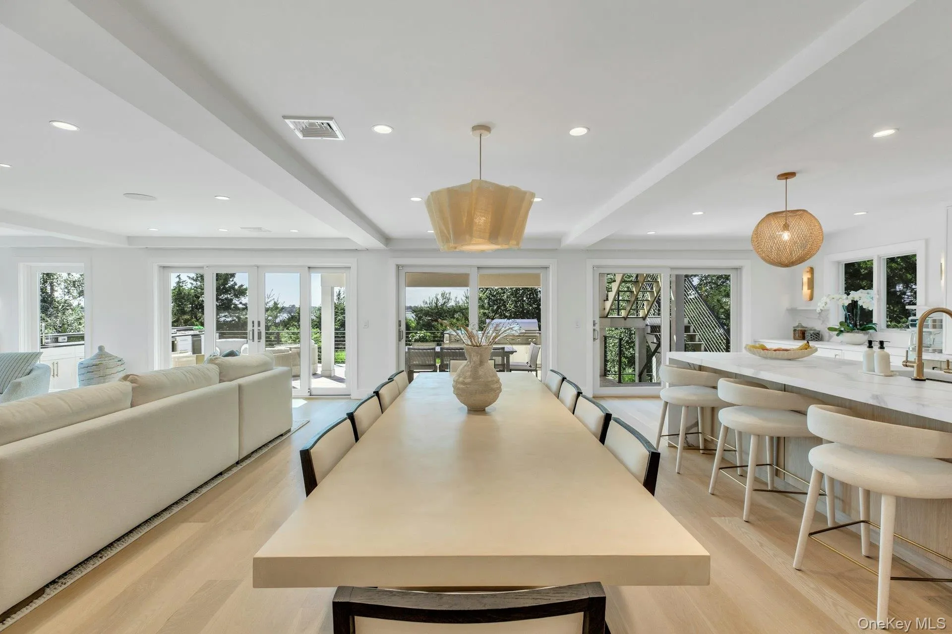 Open concept living space featuring light wood-finish flooring, recessed lighting, and multiple sliding glass doors Open concept living space featuring light wood-finish flooring, recessed lighting, and multiple sliding glass doors
