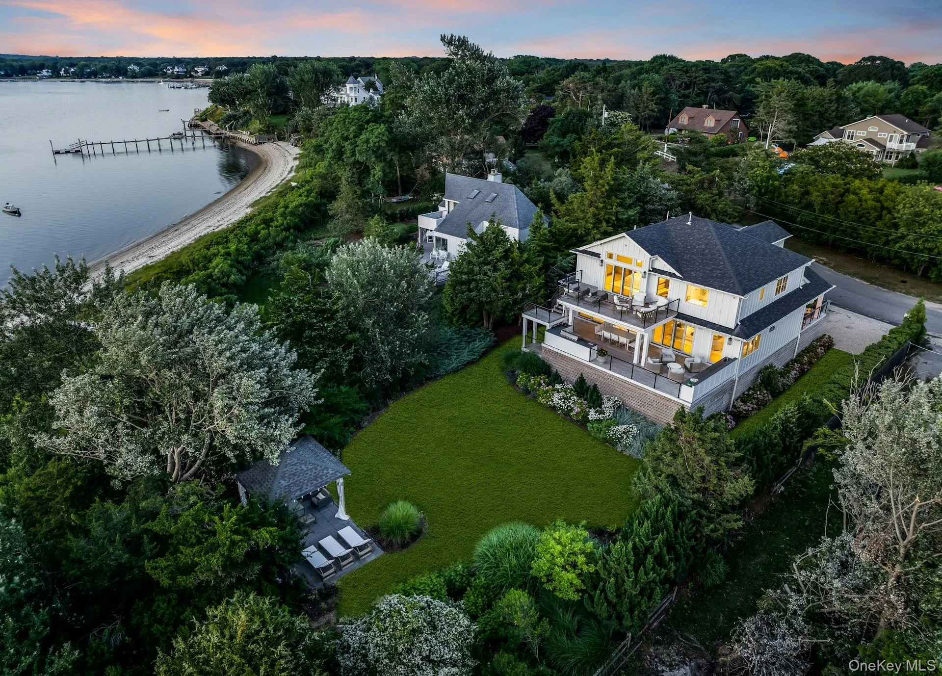 Waterfront residence featuring multiple expansive outdoor decks, a large manicured lawn, a detached gazebo, and a private beach with a dock Waterfront residence featuring multiple expansive outdoor decks, a large manicured lawn, a detached gazebo, and a private beach with a dock