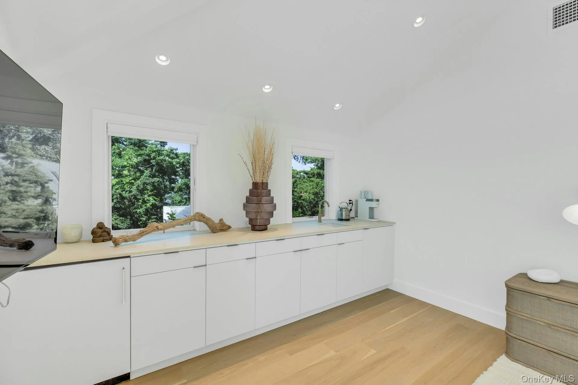 Built-in cabinetry with a light-toned countertop, integrated sink, and contemporary faucet Built-in cabinetry with a light-toned countertop, integrated sink, and contemporary faucet
