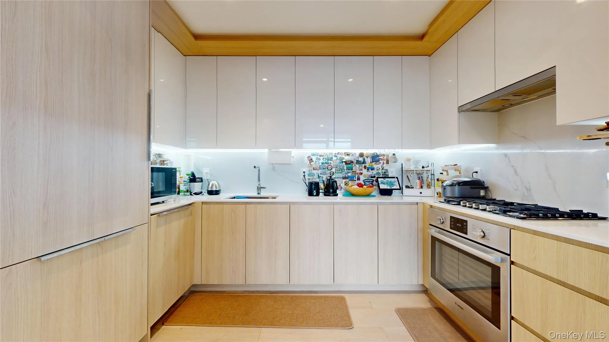 Kitchen with stainless steel appliances, modern cabinets, a sink, light countertops, and under cabinet range hood Kitchen with stainless steel appliances, modern cabinets, a sink, light countertops, and under cabinet range hood