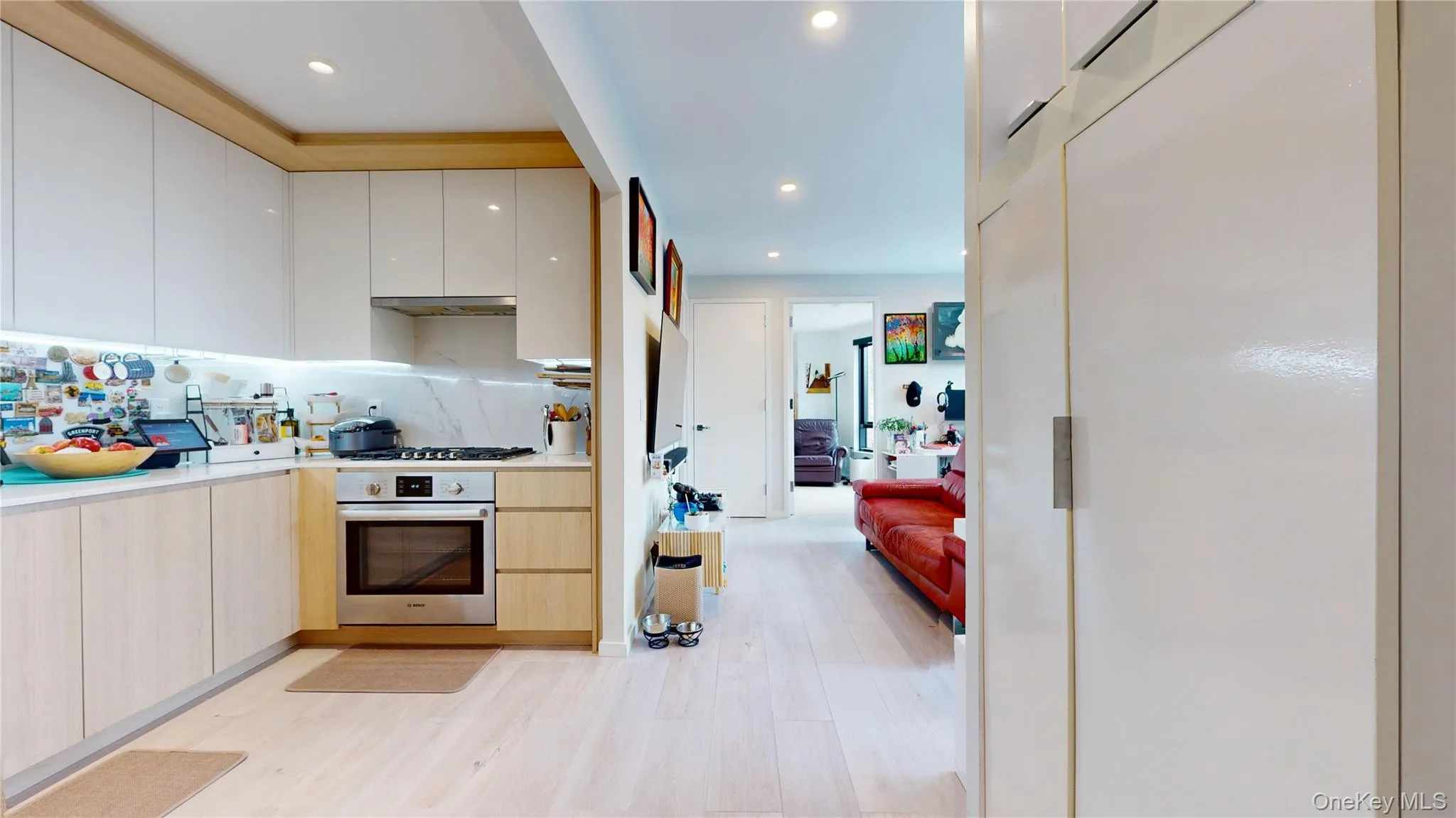 Kitchen with stainless steel oven, modern cabinets, light wood-style floors, gas stovetop, and light countertops Kitchen with stainless steel oven, modern cabinets, light wood-style floors, gas stovetop, and light countertops