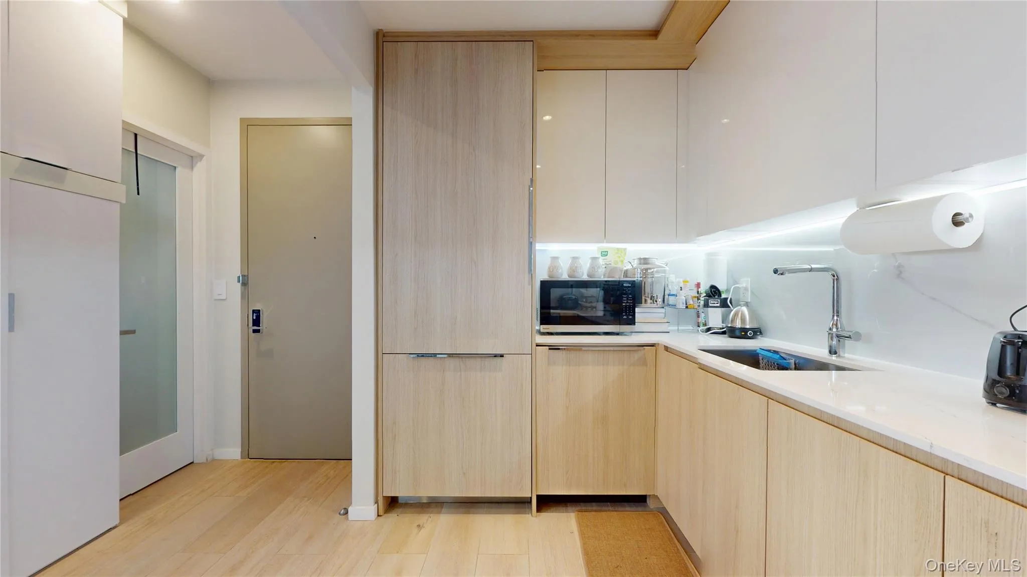 Kitchen with a sink, modern cabinets, light brown cabinets, light wood-style floors, and light stone counters Kitchen with a sink, modern cabinets, light brown cabinets, light wood-style floors, and light stone counters