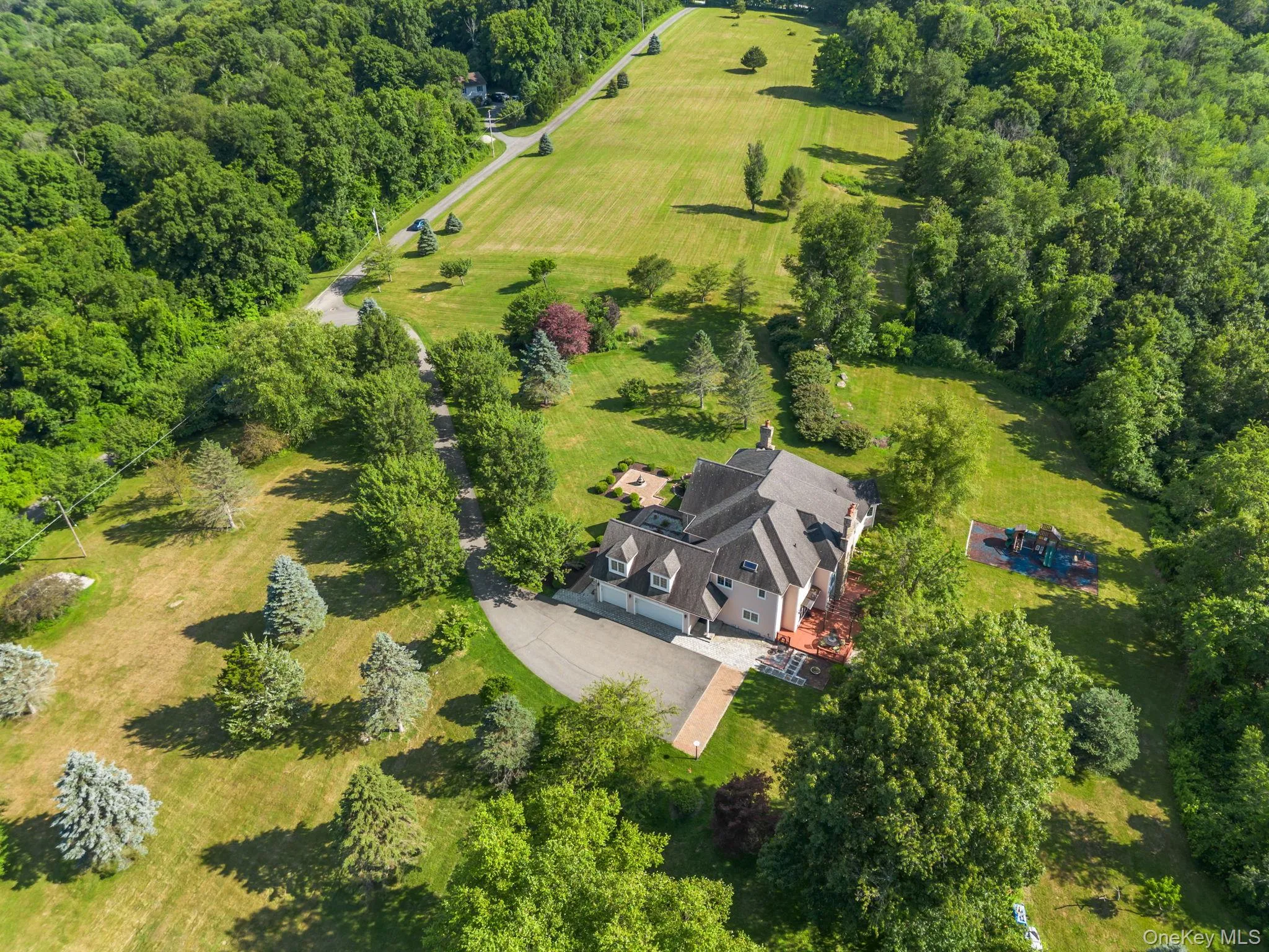 A stunning aerial perspective reveals the harmony of this country estate’s expansive grounds, lush landscaping, open spaces, and wooded backdrop. A stunning aerial perspective reveals the harmony of this country estate’s expansive grounds, lush landscaping, open spaces, and wooded backdrop.