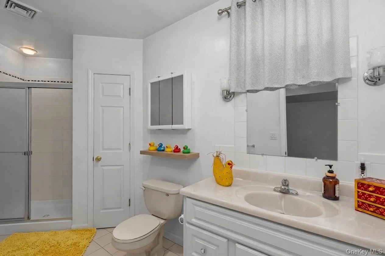 Convenient full bathroom on the lower level offering a shower, vanity, and storage Convenient full bathroom on the lower level offering a shower, vanity, and storage
