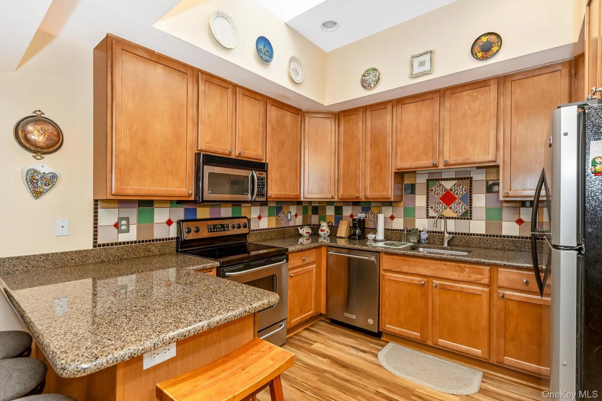 Kitchen featuring wood-finish flooring, granite countertops, and wood cabinetry Kitchen featuring wood-finish flooring, granite countertops, and wood cabinetry