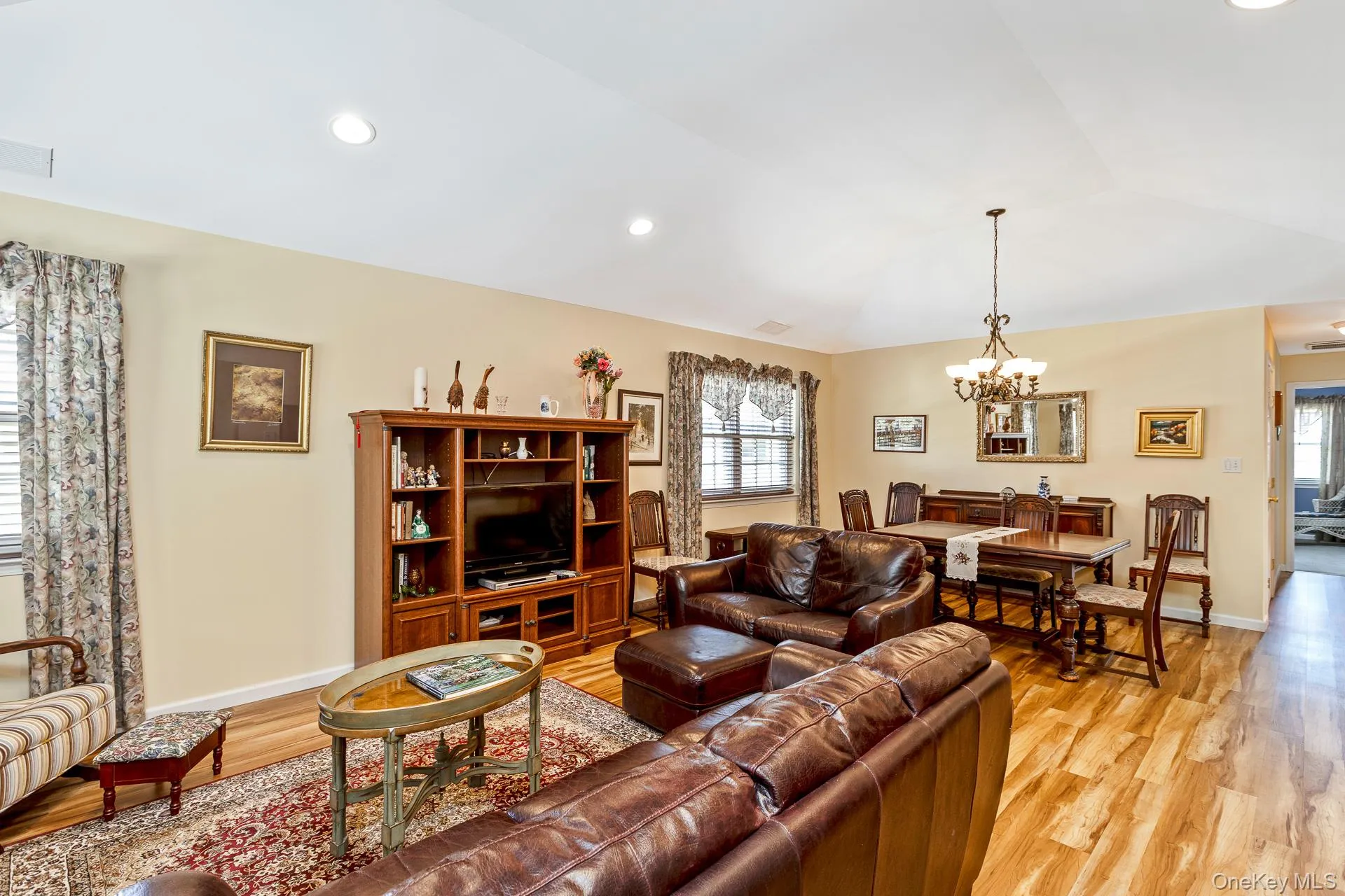 Open-concept living area with wood-finish flooring, recessed lighting, and a chandelier in the dining space Open-concept living area with wood-finish flooring, recessed lighting, and a chandelier in the dining space